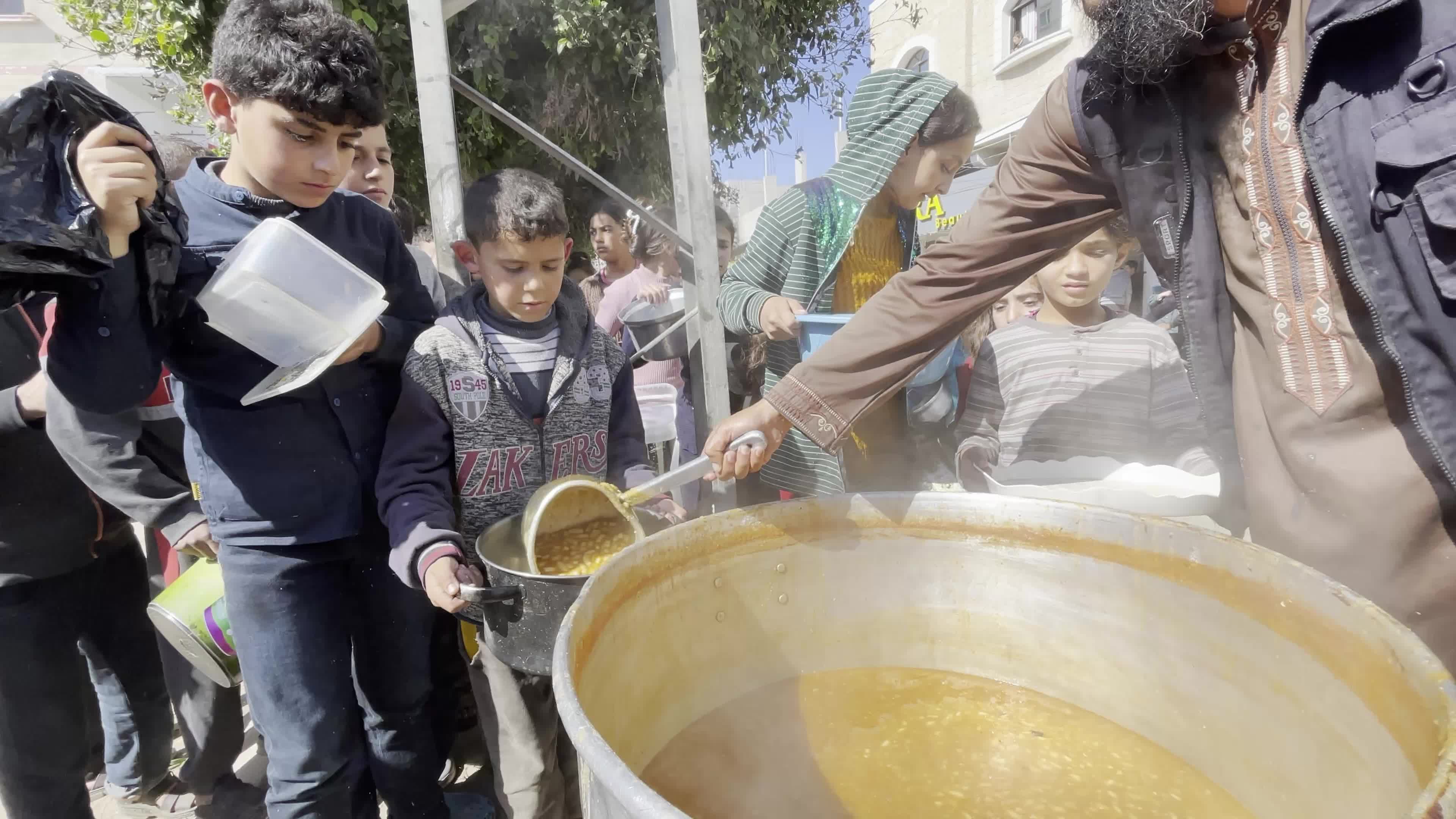 Displaced Palestinians Receive Food at Refugee Camp in Deir al-Balah Amid Israel-Hamas Conflict