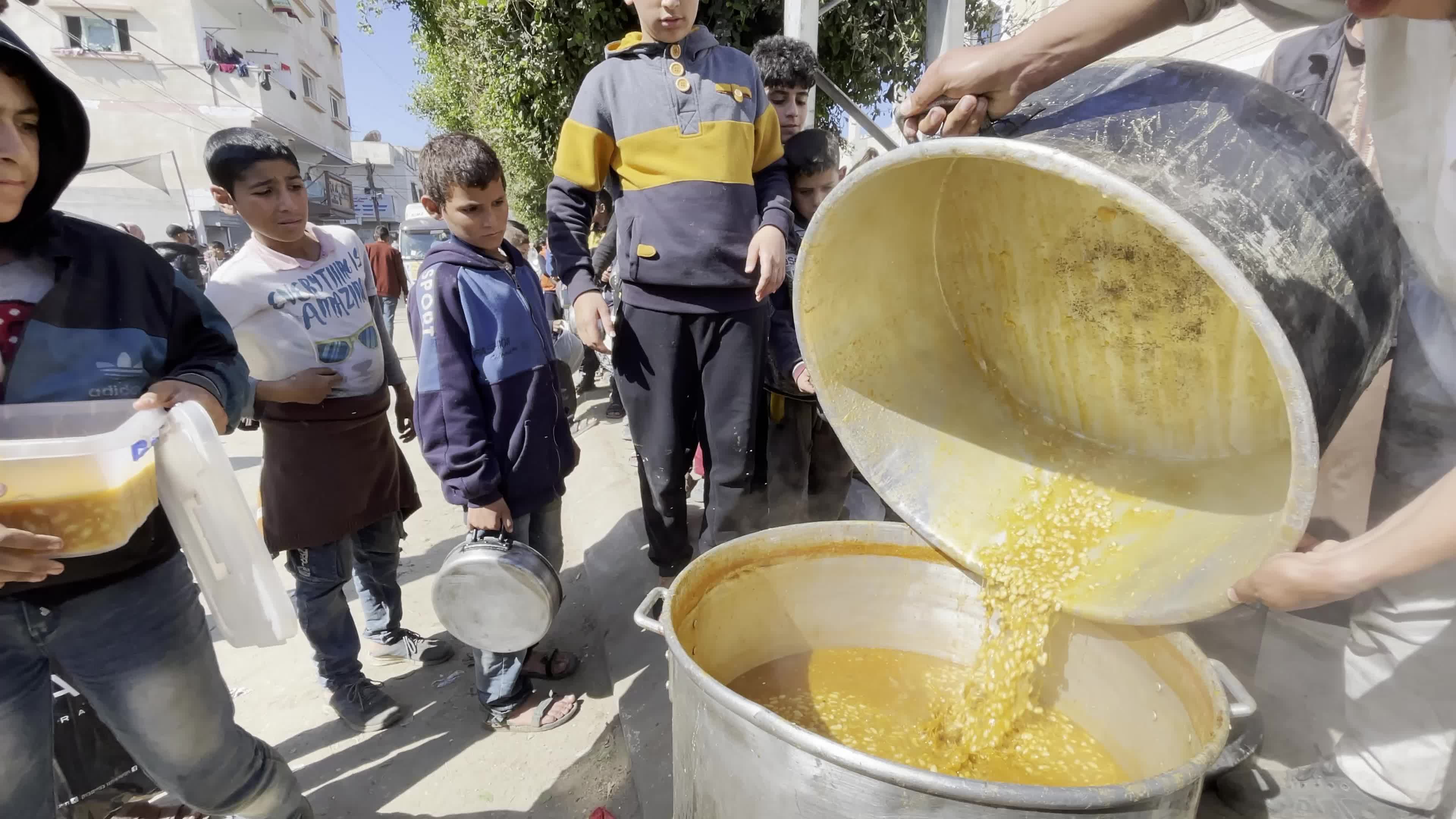 Displaced Palestinians Receive Food at Refugee Camp in Deir al-Balah Amid Israel-Hamas Conflict