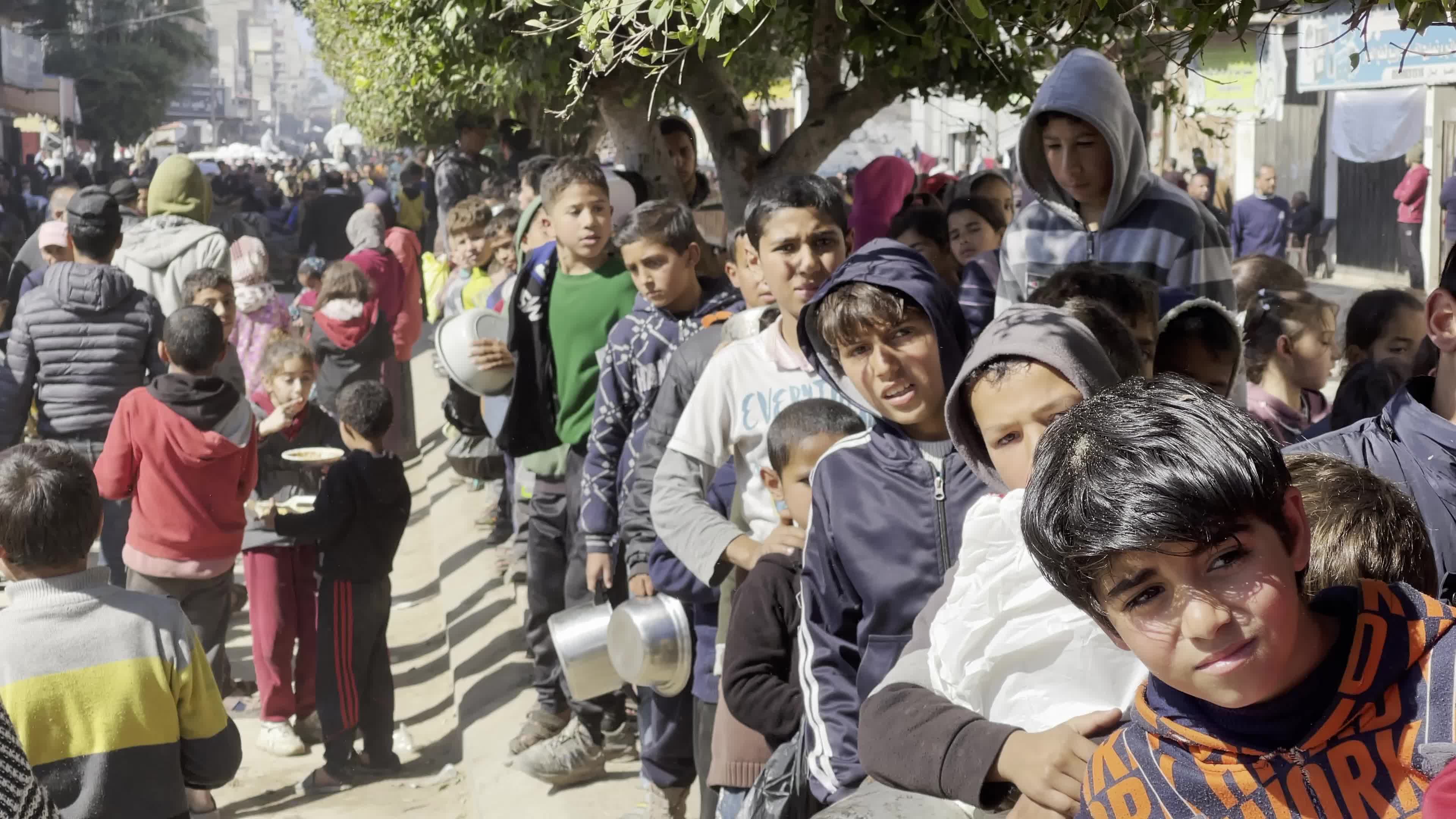 Displaced Palestinians Receive Food at Refugee Camp in Deir al-Balah Amid Israel-Hamas Conflict
