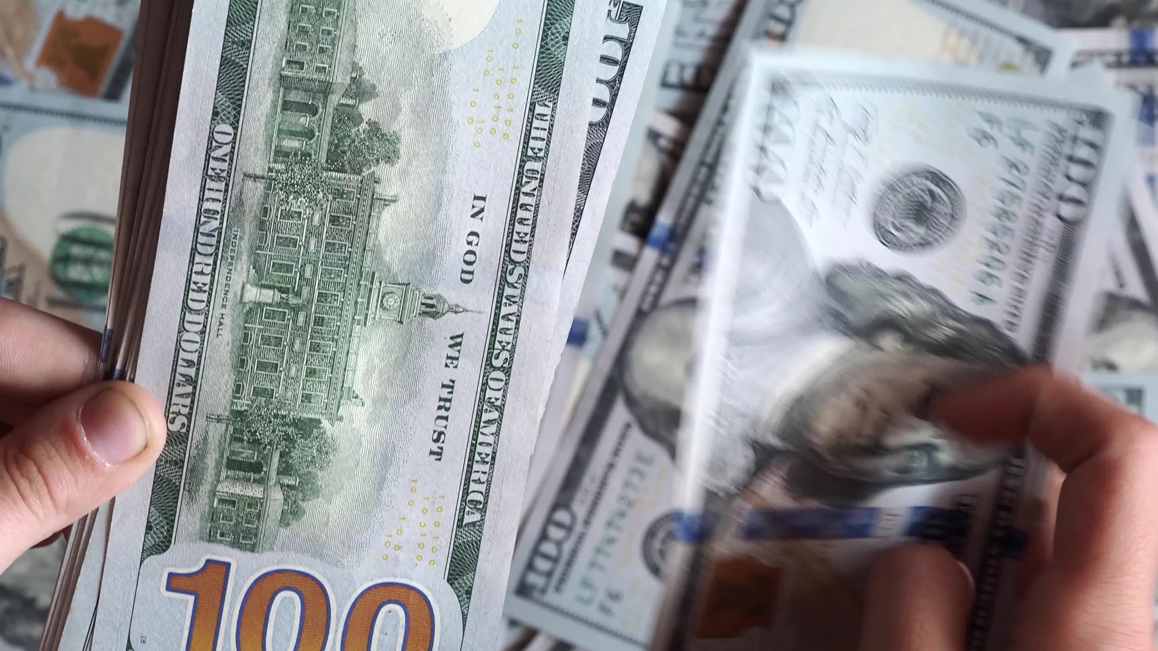 Person counts 100 dollar banknotes in hands