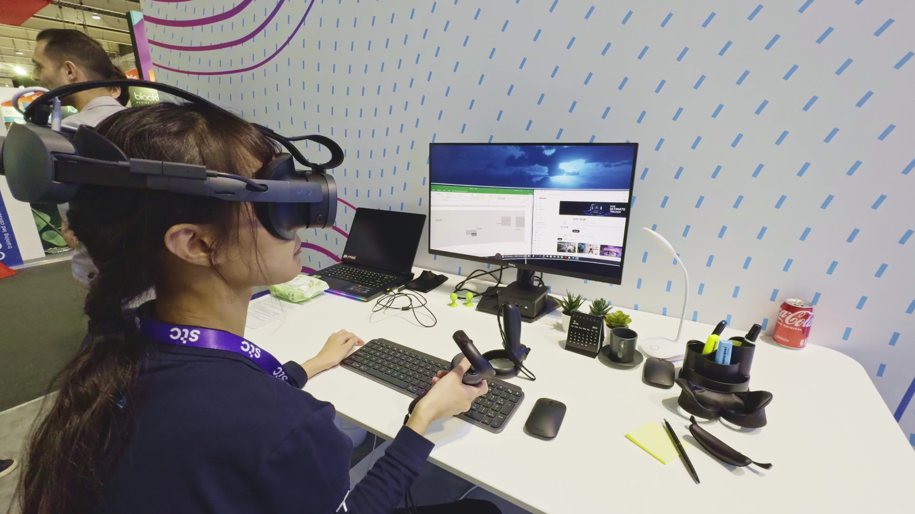 BARCELONA, SPAIN - FEBRUARY 28: A woman using the  HTC VIVE XR Elite, the latest extended reality headset developed by the Chinese manufacturer HTC Vive that incorporates an accessory for full facial features tracking, to work in a virtual office with multi-screens during the Mobile World Congress 2024 on February 28, 2024, in Barcelona, Spain.