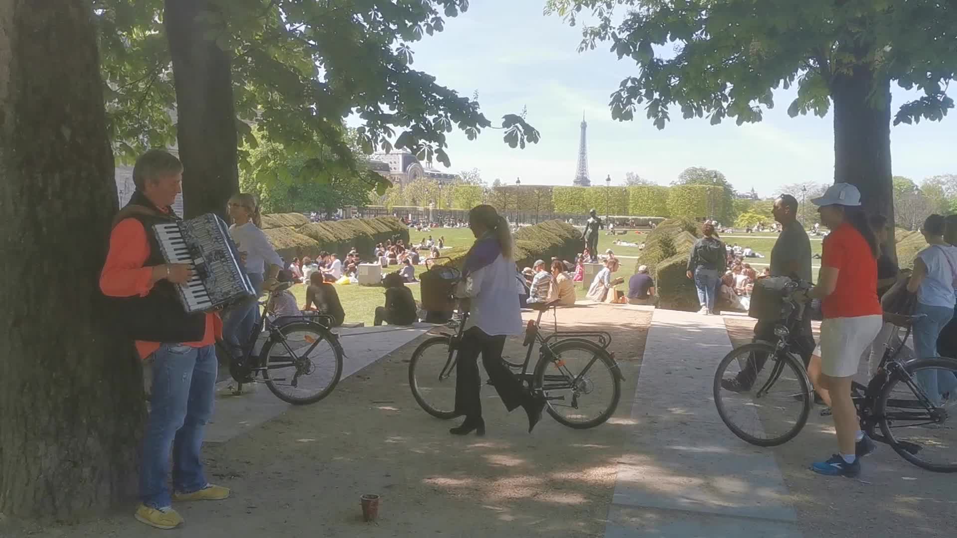 Tourists and Parisians enjoying the sun at the Tuileries Gardens and the Louvre in Paris 