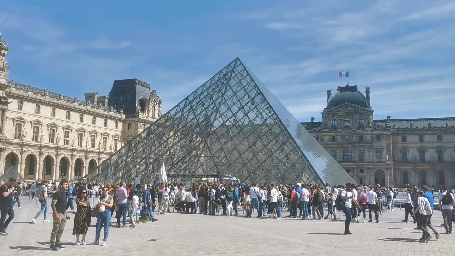 Tourists and Parisians enjoying the sun at the Tuileries Gardens and the Louvre in Paris 