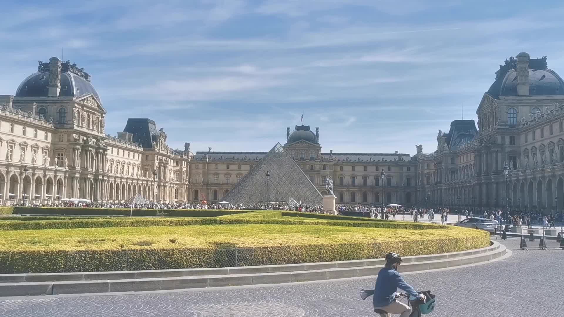 Tourists and Parisians enjoying the sun at the Tuileries Gardens and the Louvre in Paris 