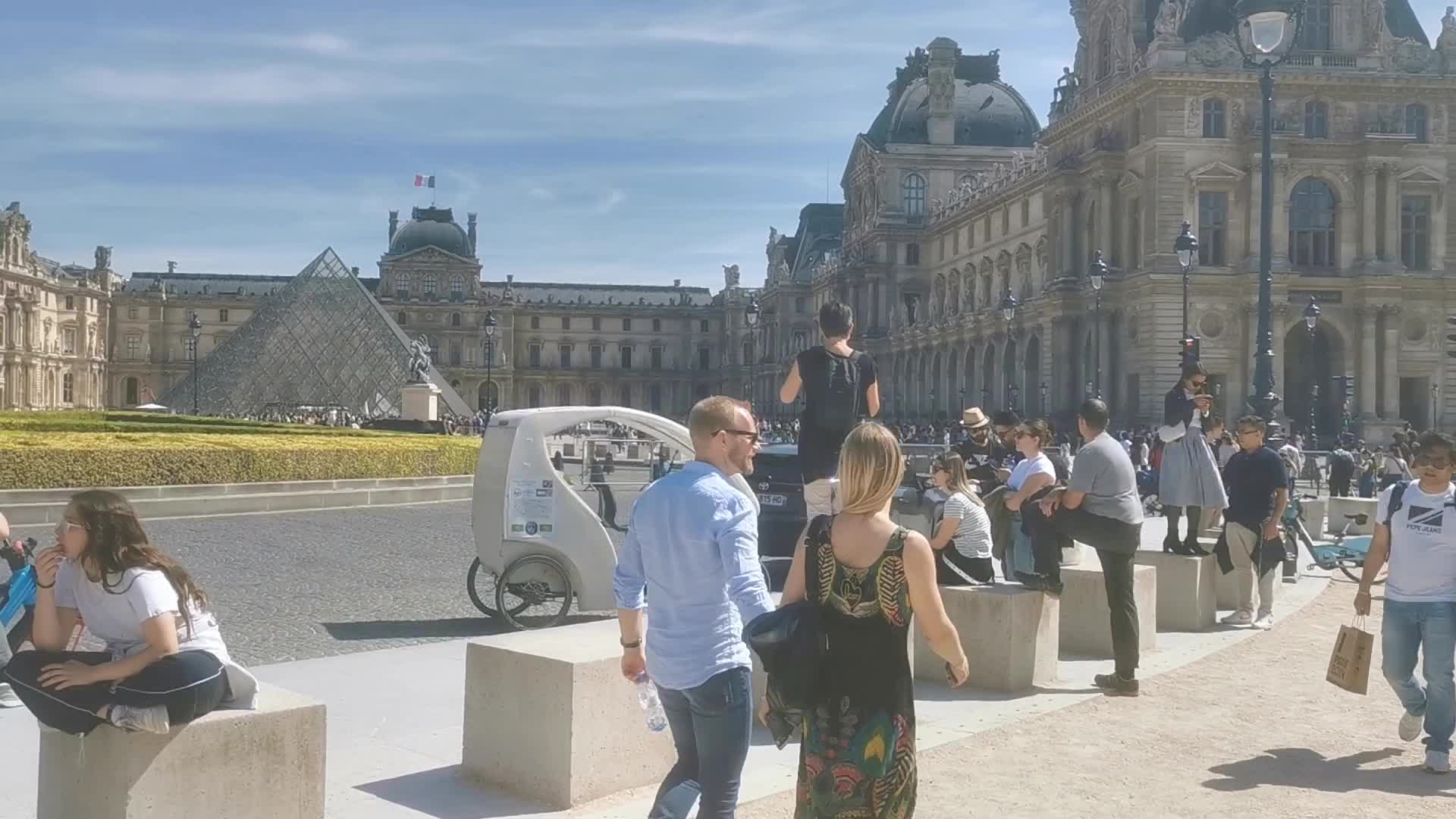 Tourists and Parisians enjoying the sun at the Tuileries Gardens and the Louvre in Paris 