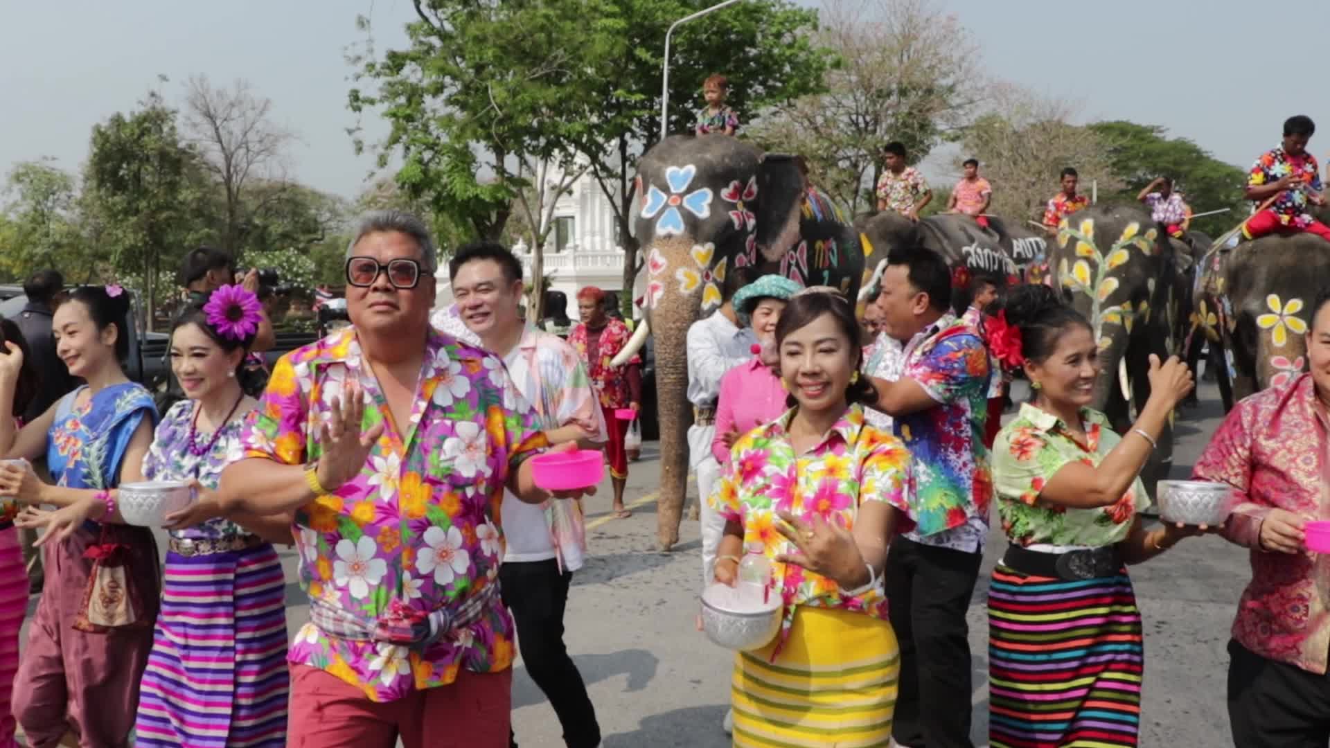 Tourists enjoy while play water battle with elephants
