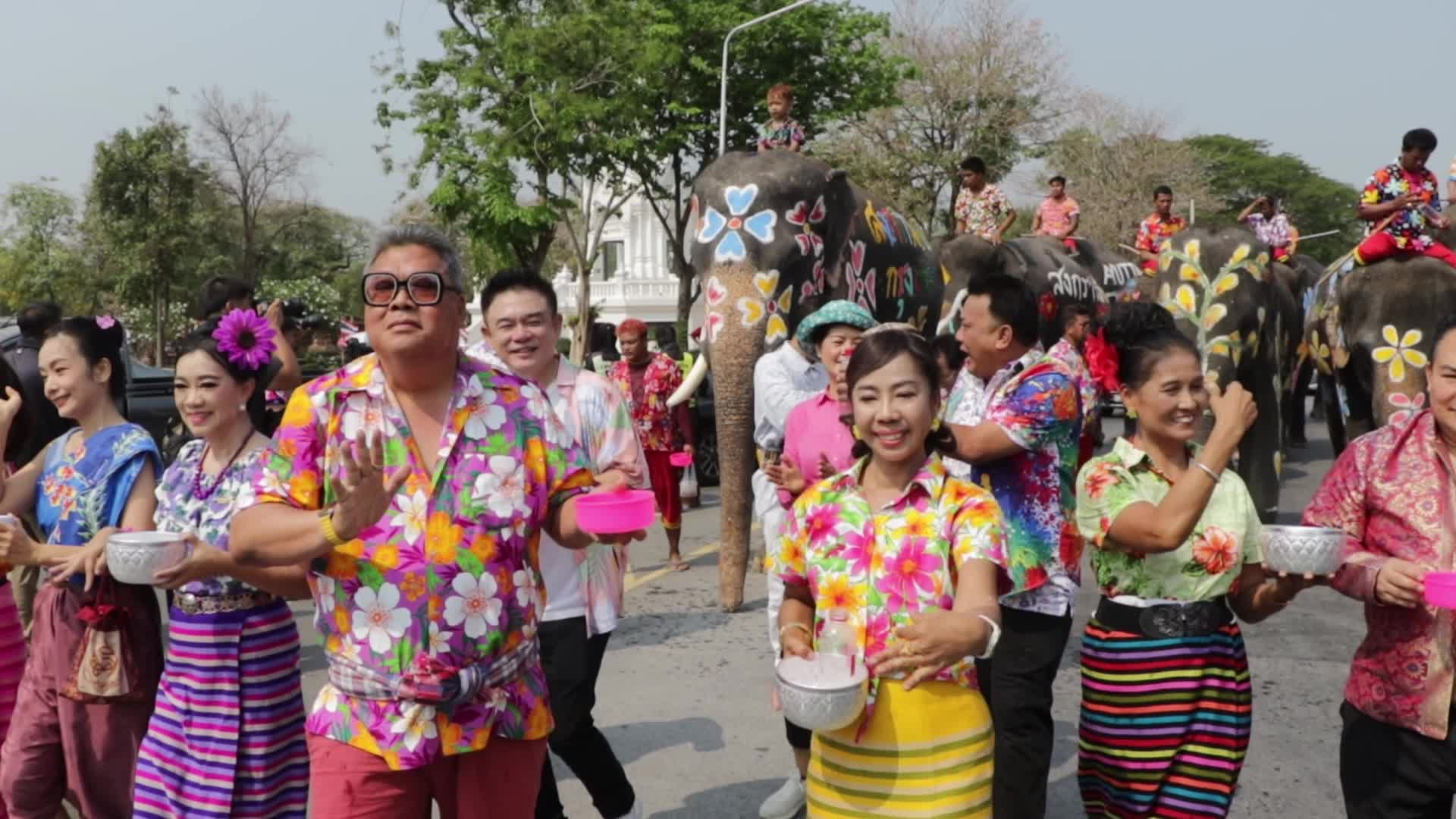 Tourists enjoy while play water battle with elephants