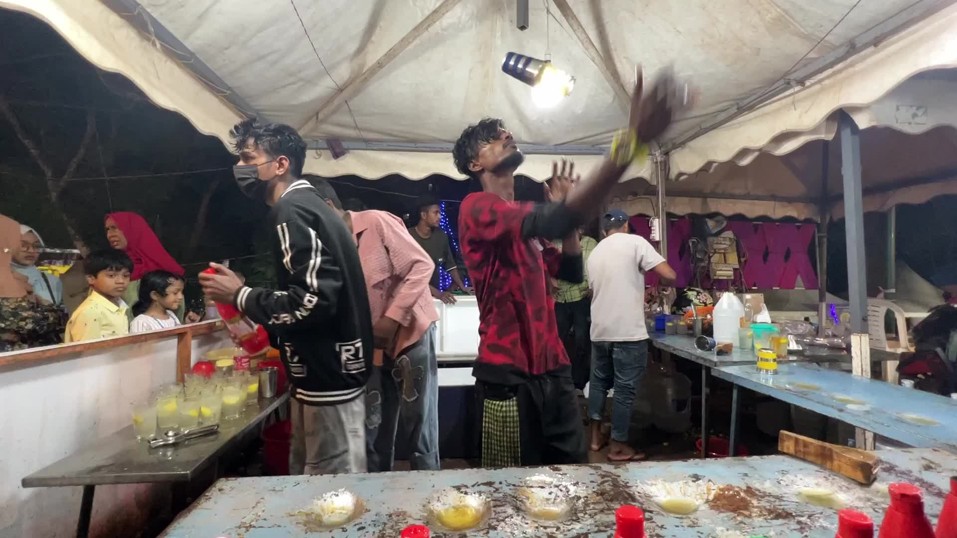 Men perform tricks while they prepare Kulukki Sarbath