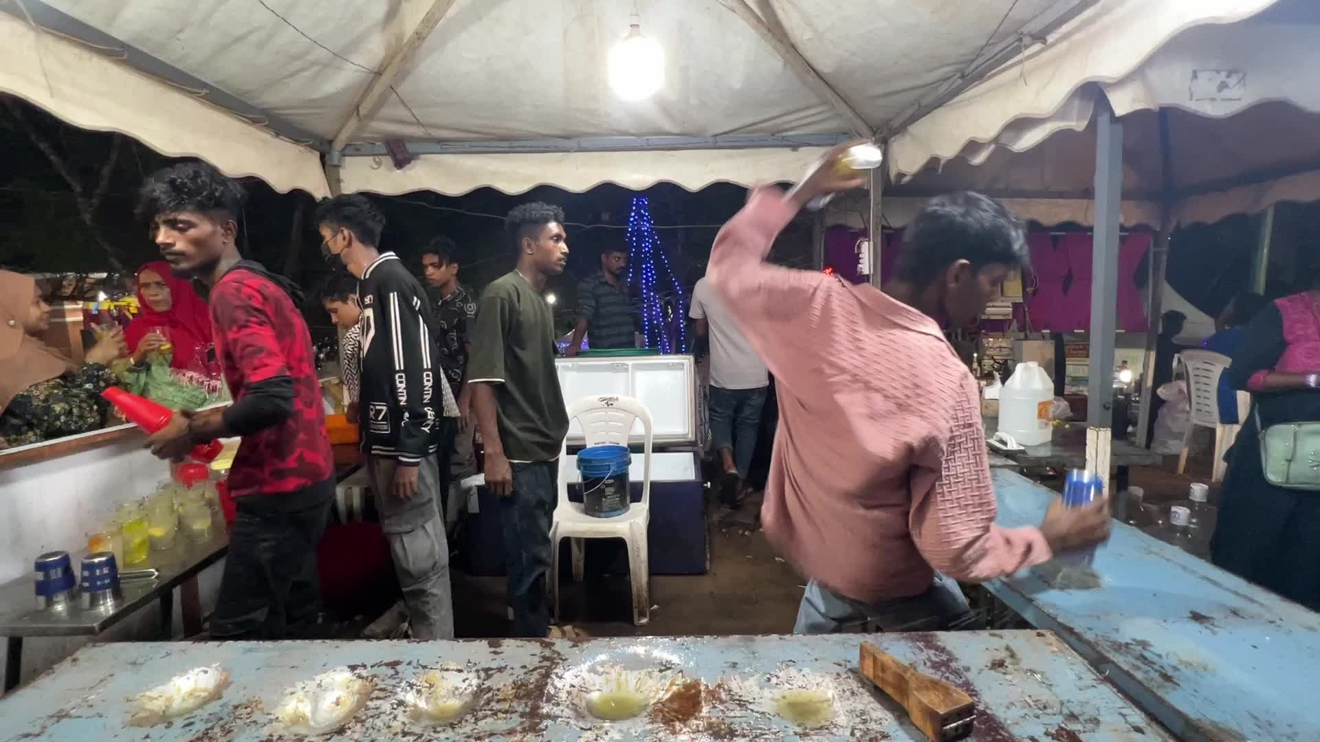 Men perform tricks while they prepare Kulukki Sarbath