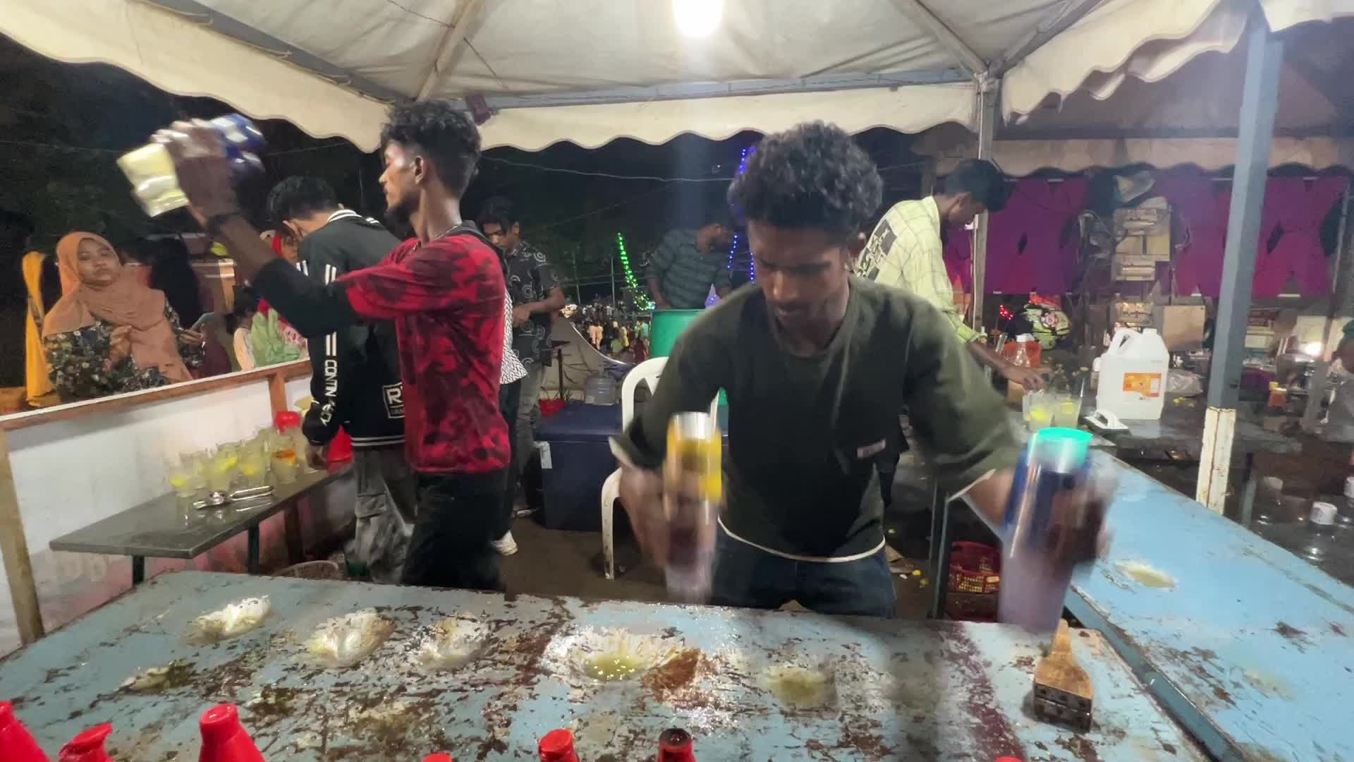Men perform tricks while they prepare Kulukki Sarbath