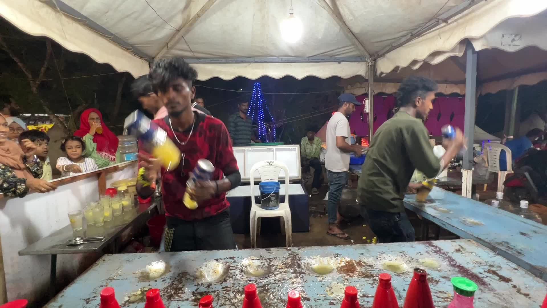 Men perform tricks while they prepare Kulukki Sarbath