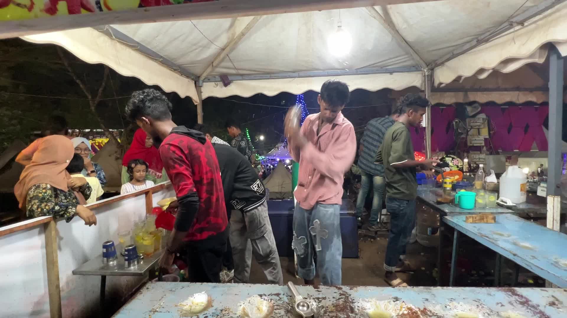 Men perform tricks while they prepare Kulukki Sarbath
