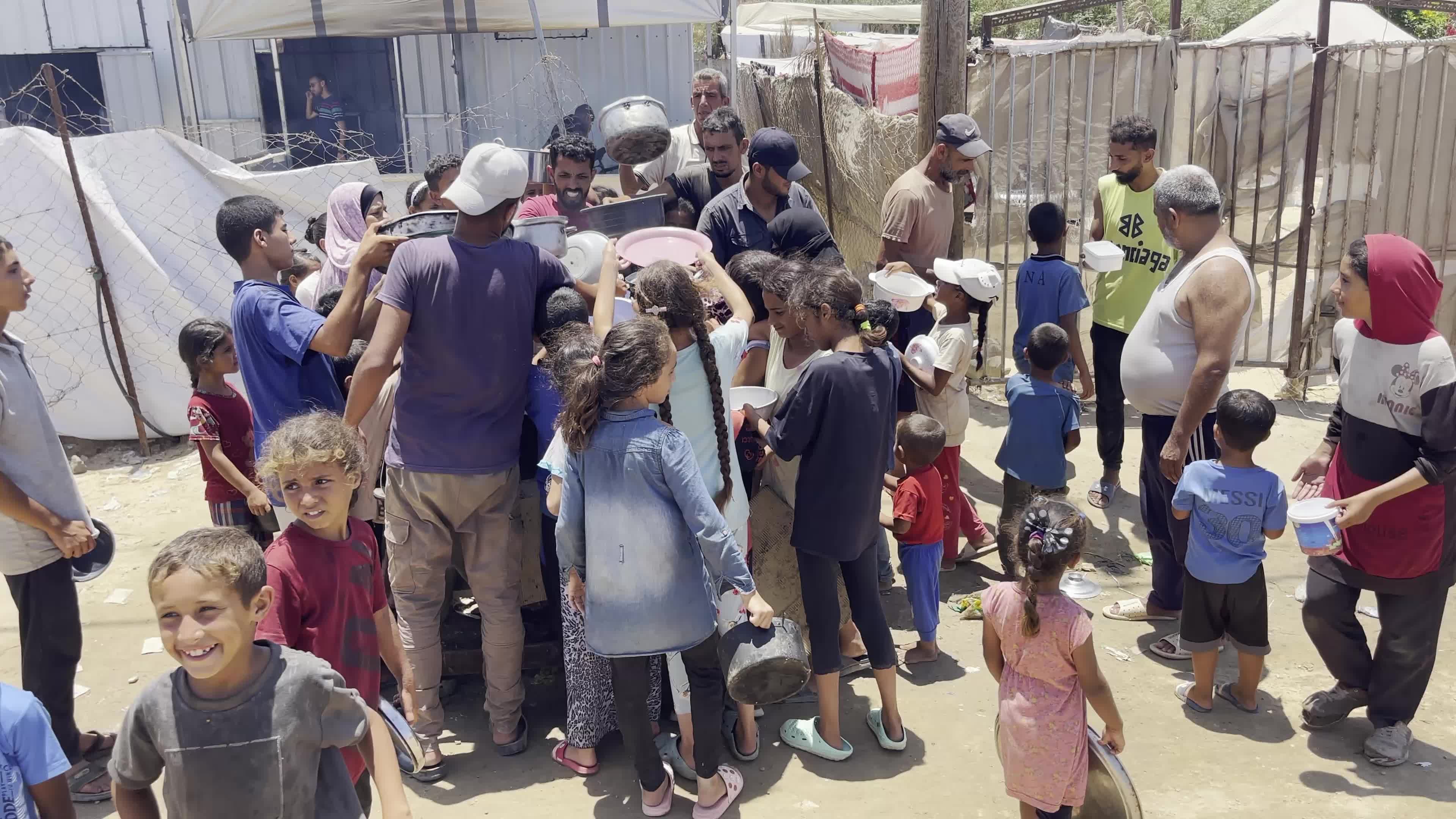 Displaced Palestinian Children Await Food Distribution Amid Ongoing Gaza Conflict