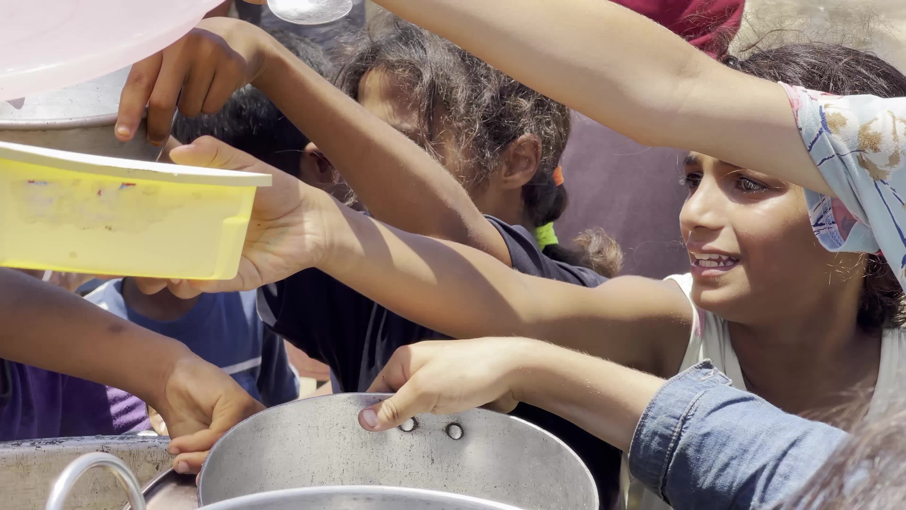 Displaced Palestinian Children Await Food Distribution Amid Ongoing Gaza Conflict