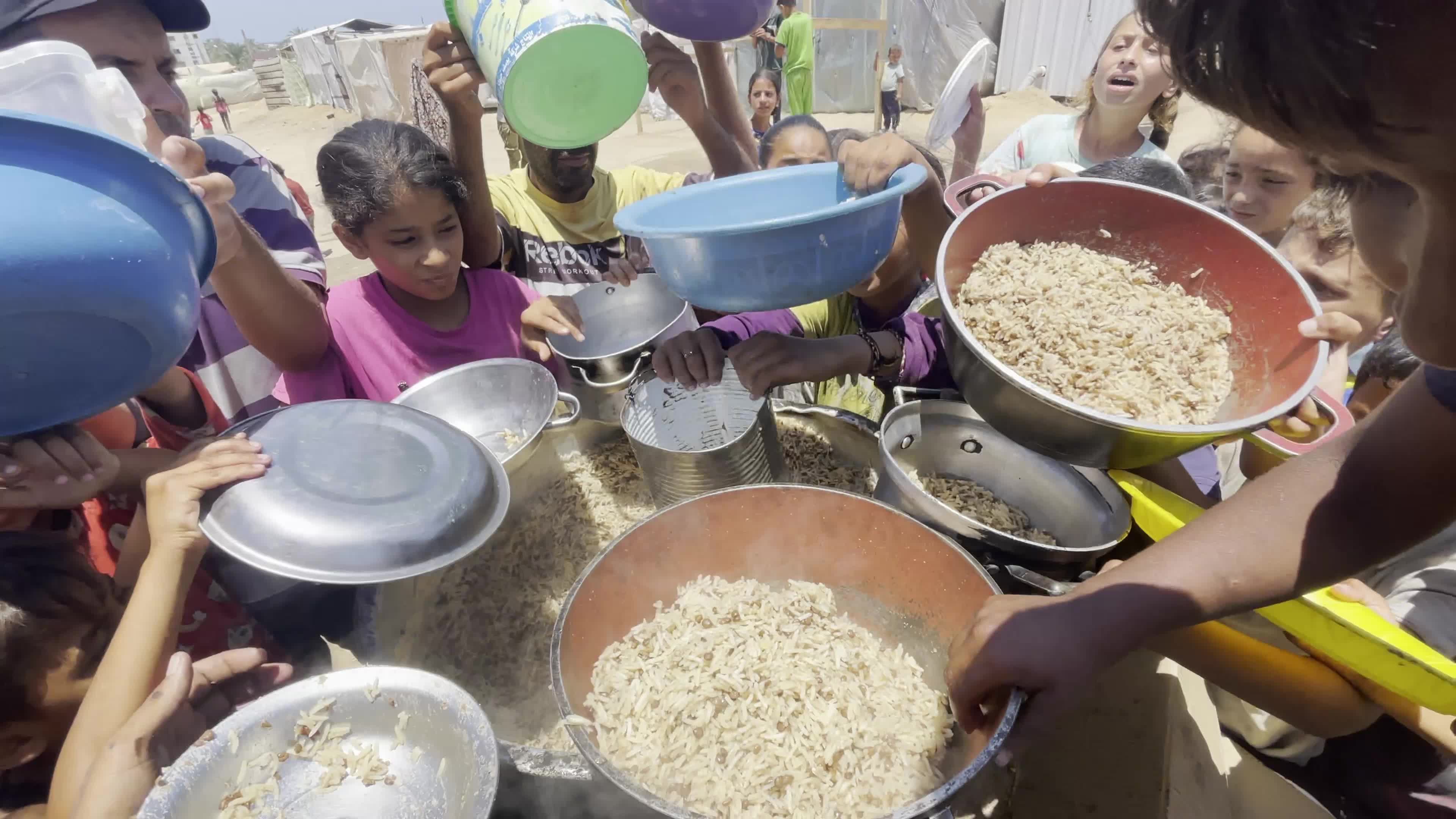 Displaced Palestinian Children Await Food Distribution Amid Ongoing Gaza Conflict