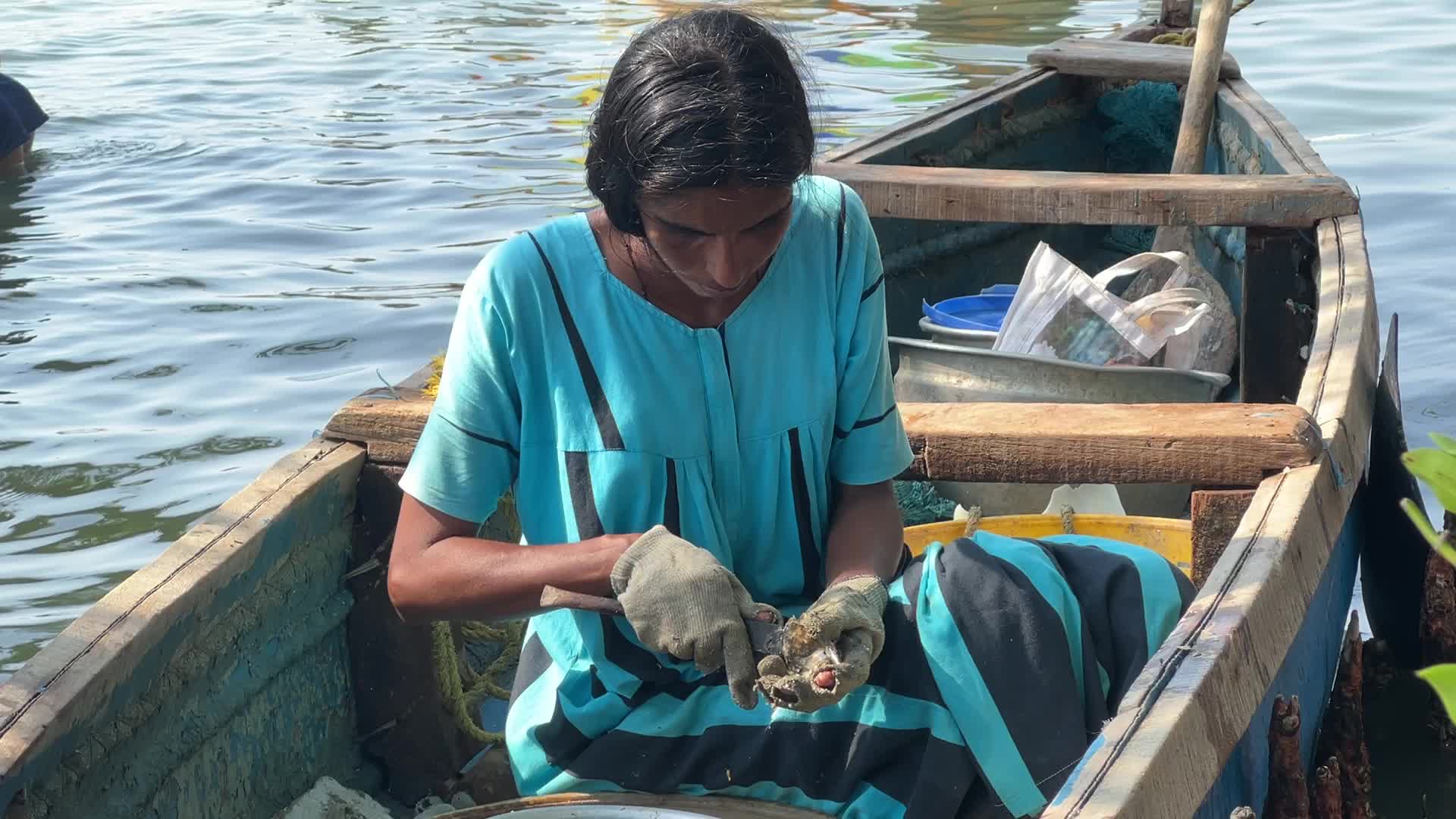 Fisherwoman shucking mussels in Kerala