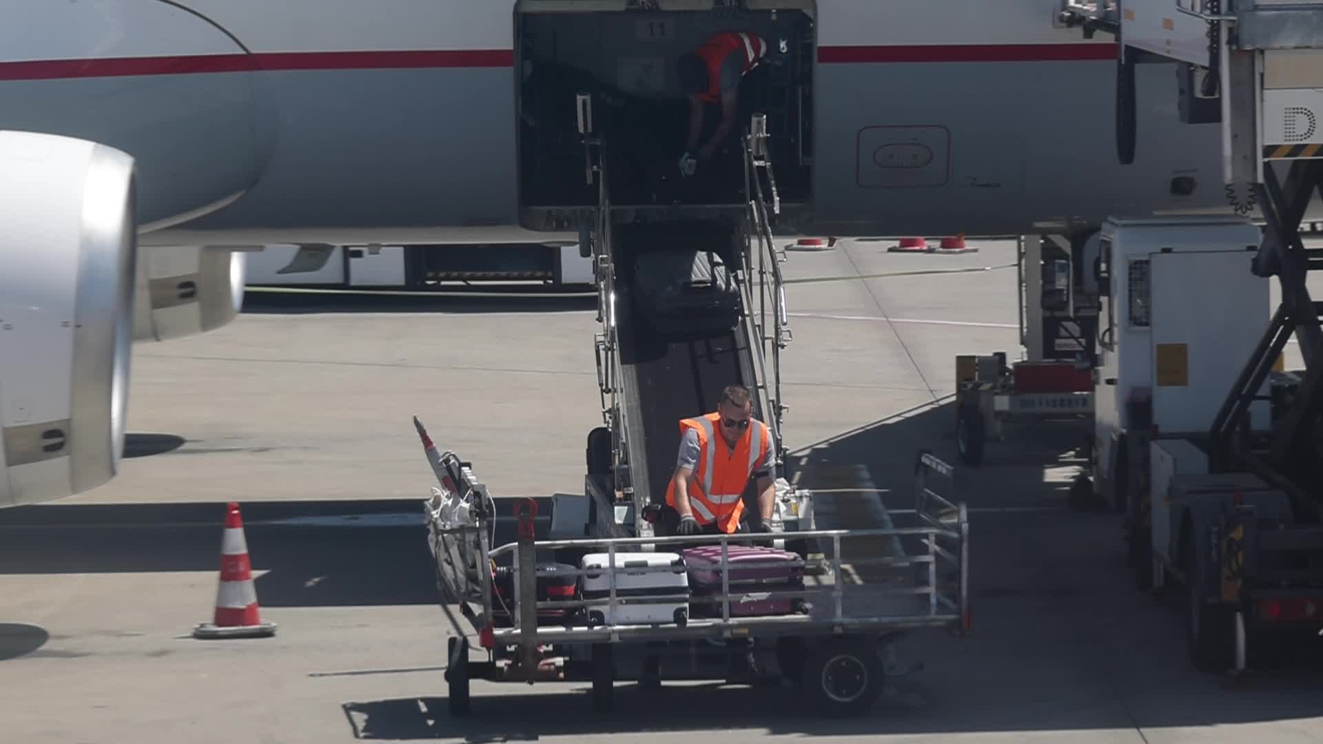Airport workers unload luggage