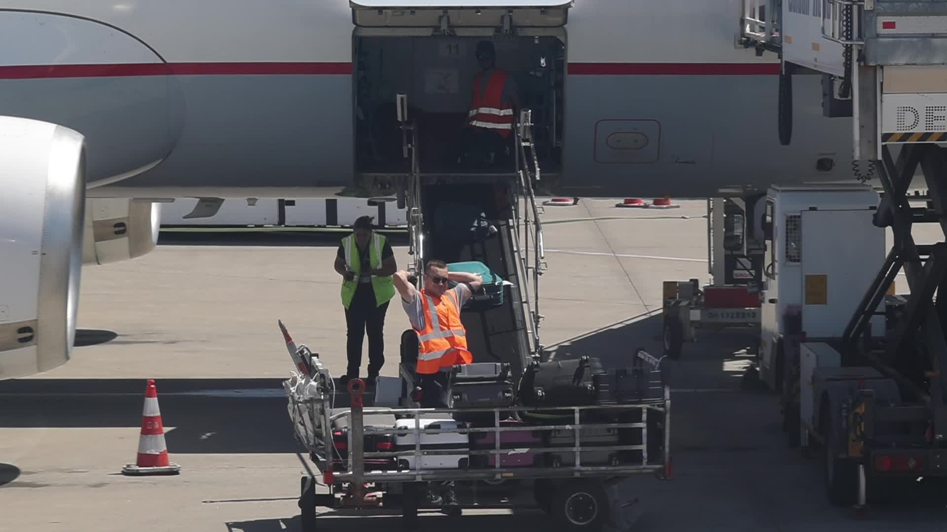 Airport workers unload luggage