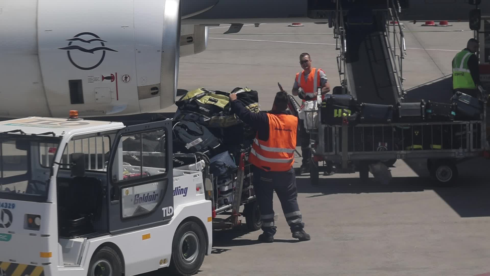 Airport workers unload luggage