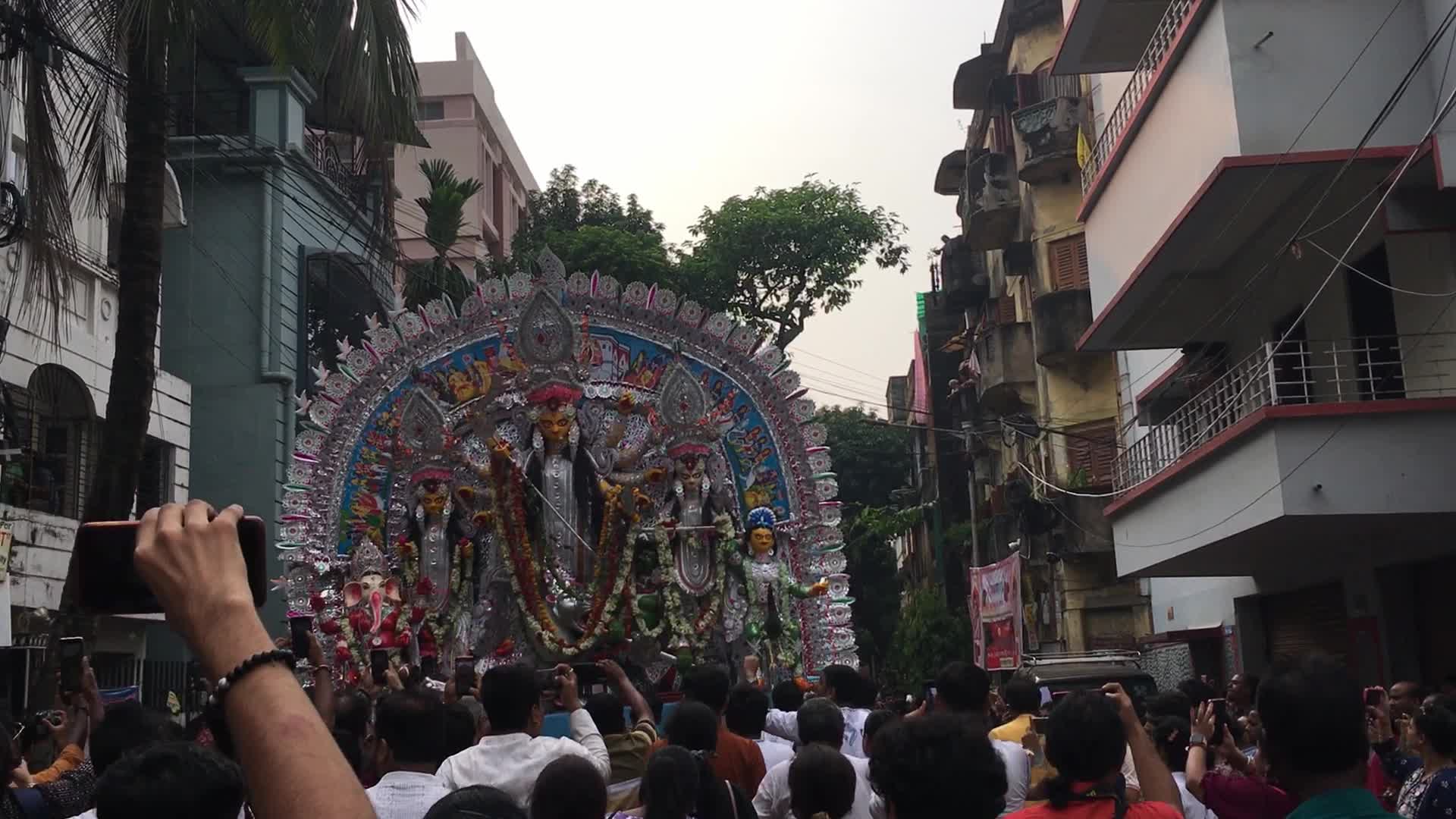 Devotees carry Durga idol through a busy street