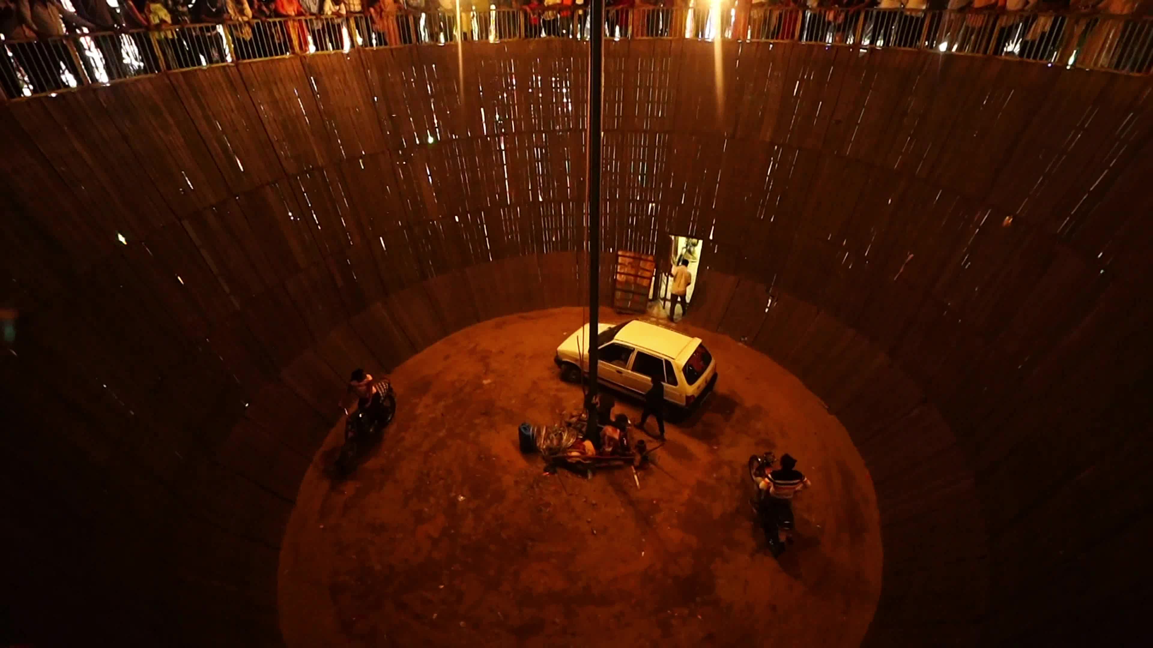Stuntmen ride their vehicles along the wall of a wooden structure during the 'Well of Death' show