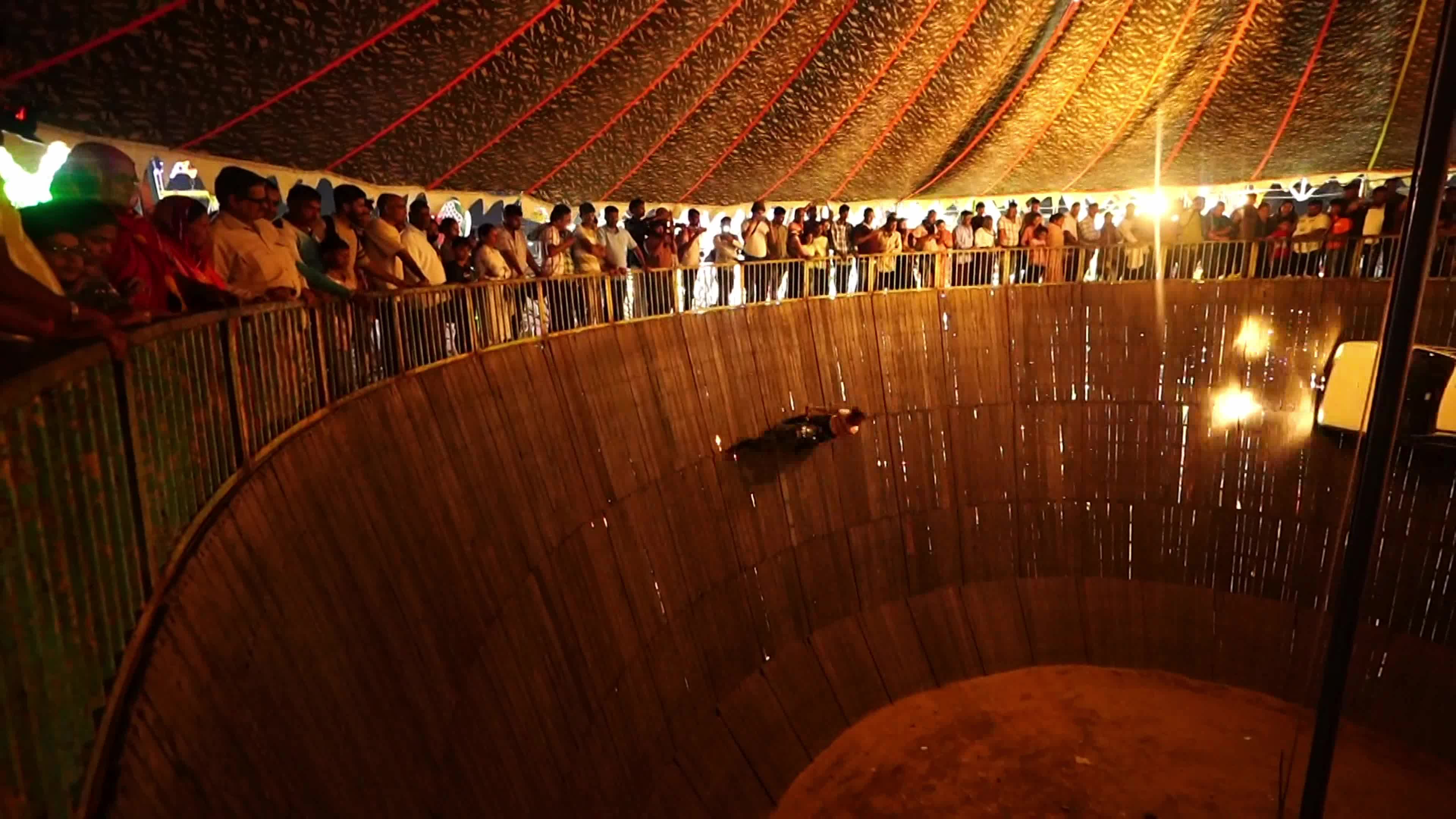 Stuntmen ride their vehicles along the wall of a wooden structure during the 'Well of Death' show