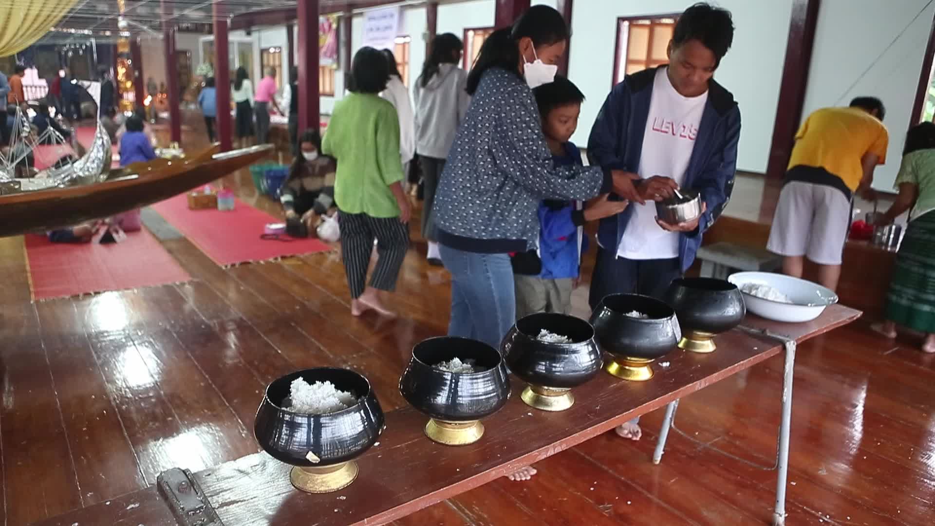 Villagers pray and join in making merit