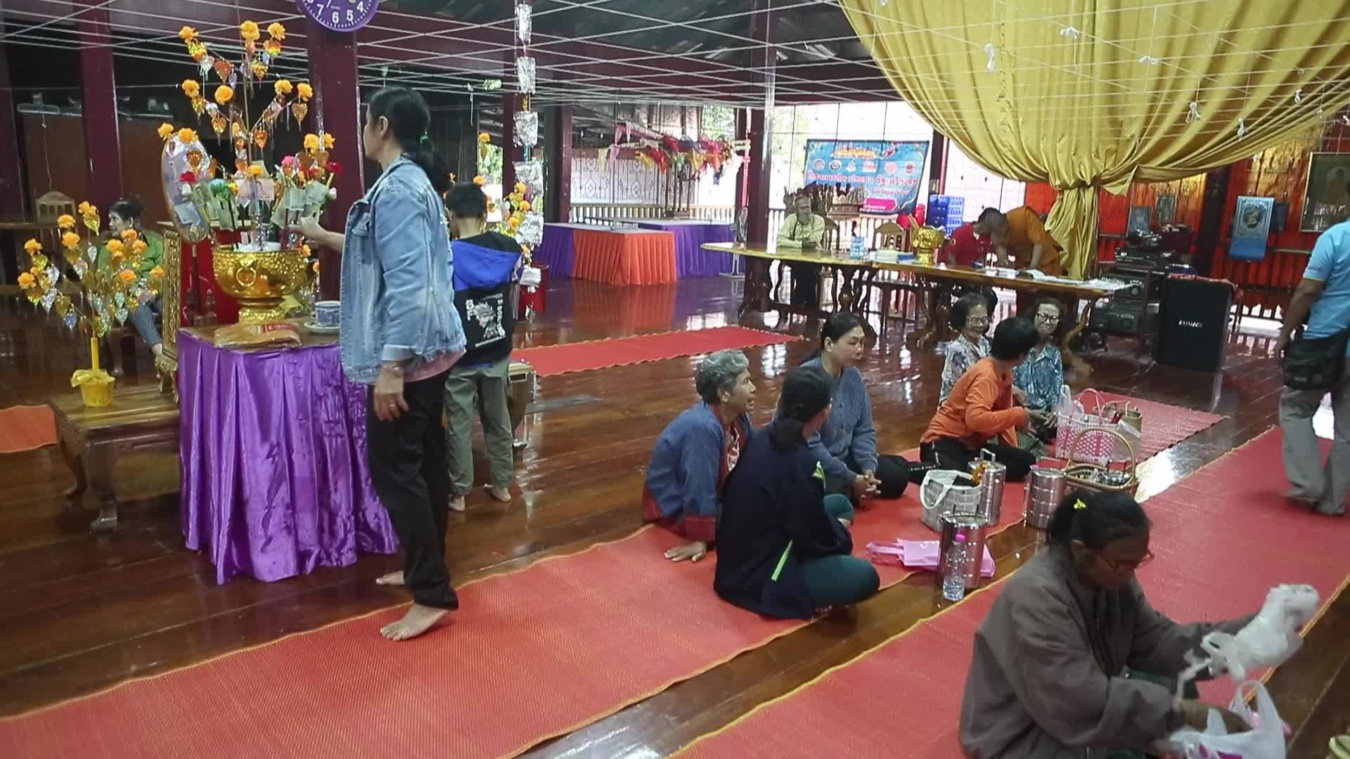 Villagers pray and join in making merit