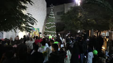 Palestinian Christians attend a Christmas tree lighting celebration