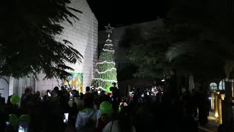 Palestinian Christians attend a Christmas tree lighting celebration
