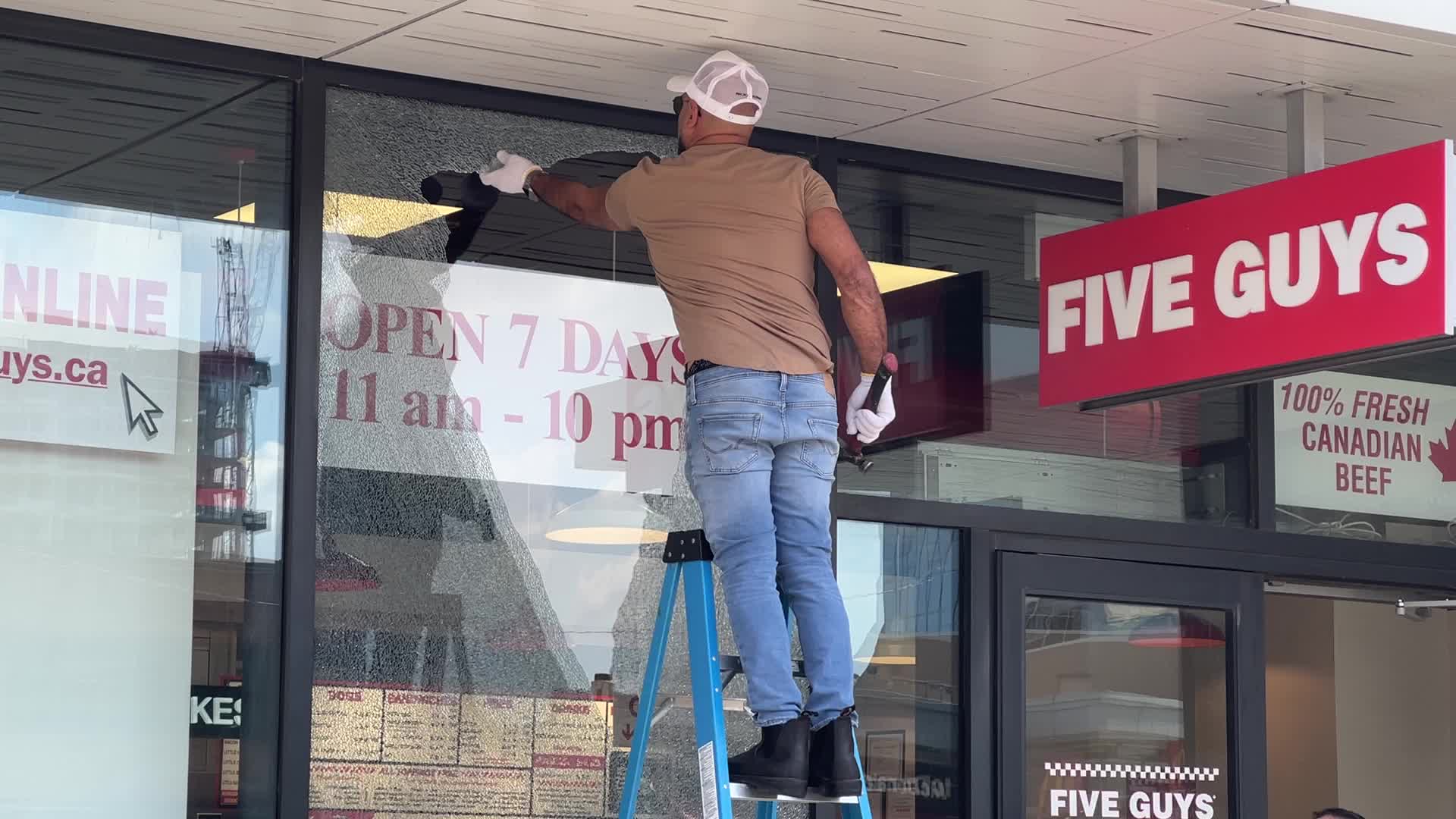 Workers repair a restaurant window damaged by gunshots in Toronto