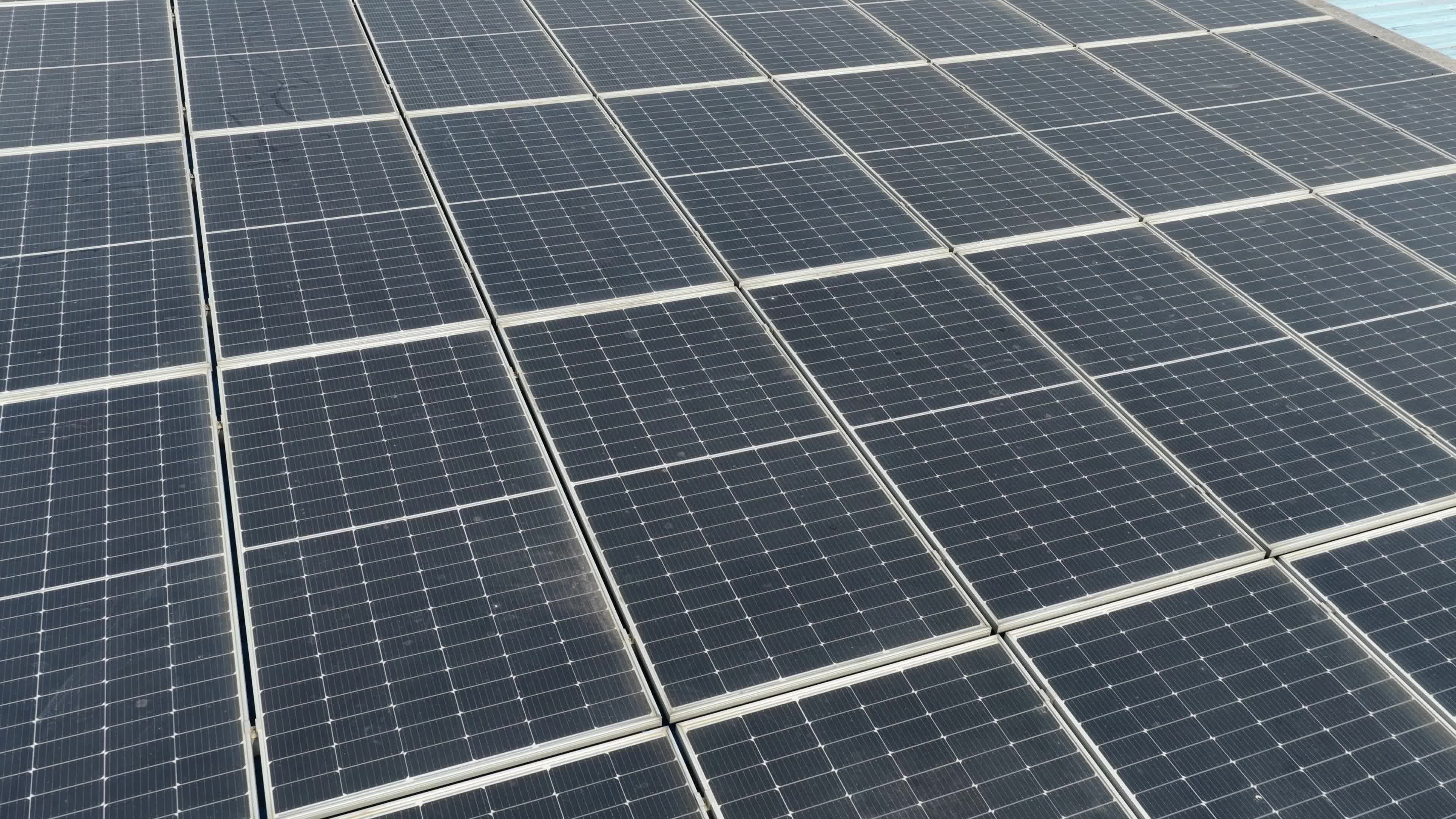 4K Aerial Drone View of Solar Panels Installed on Blue Tin Roof of Industrial Building in India