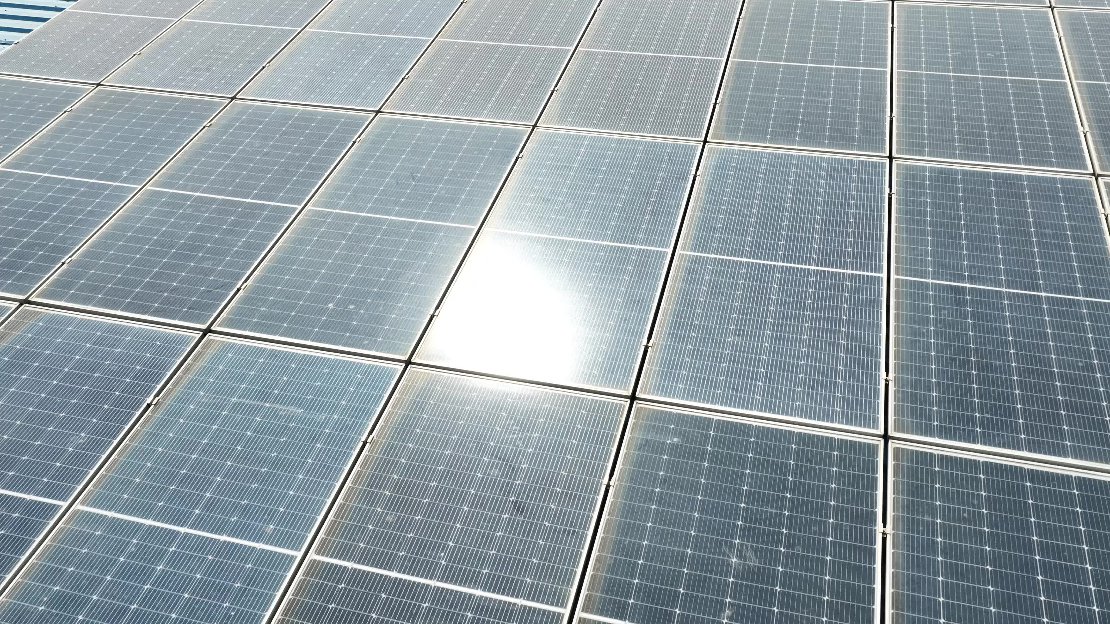 4K Aerial Drone View of Solar Panels Installed on Blue Tin Roof of Industrial Building in India