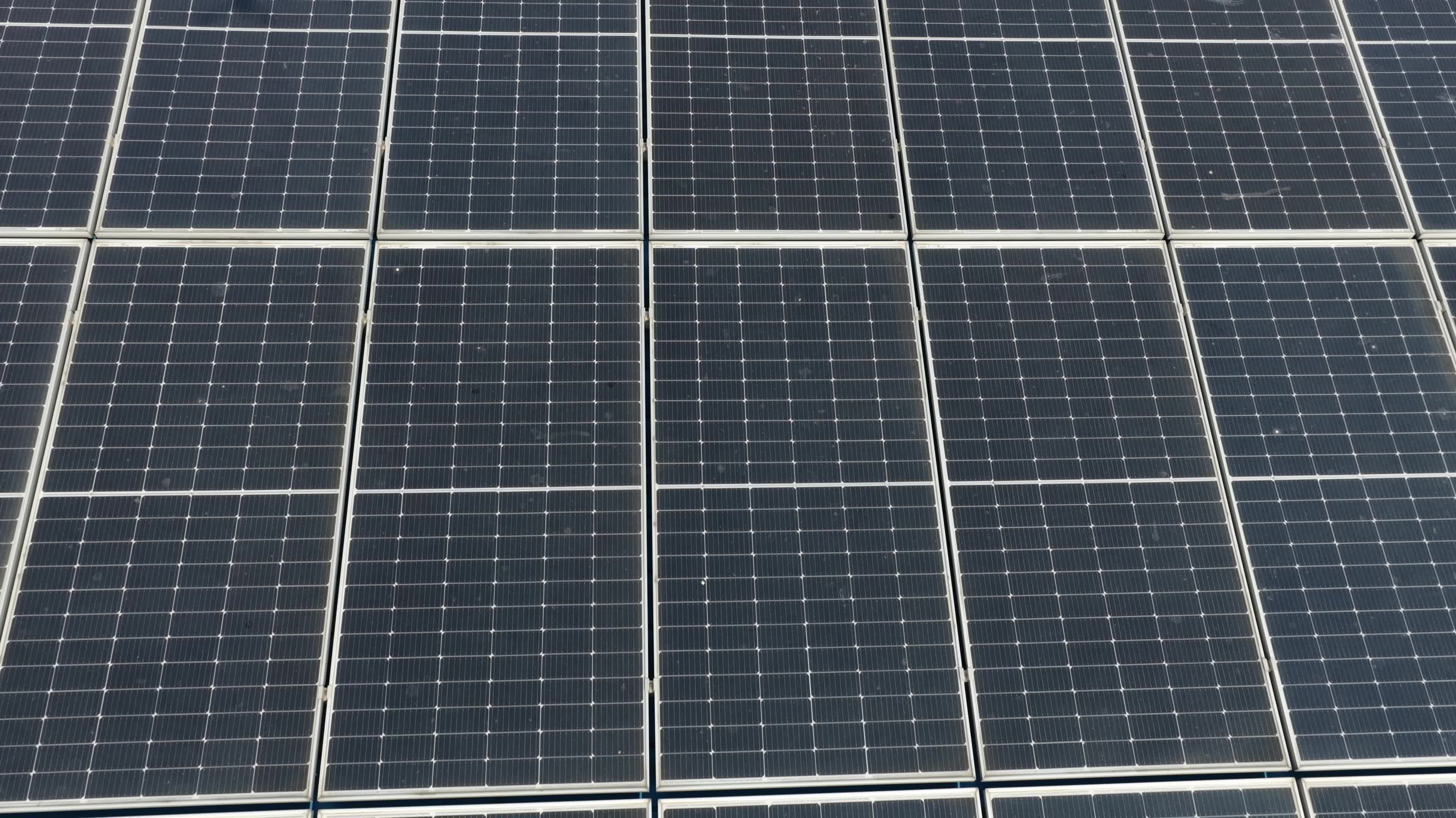 4K Aerial Drone View of Solar Panels Installed on Blue Tin Roof of Industrial Building in India