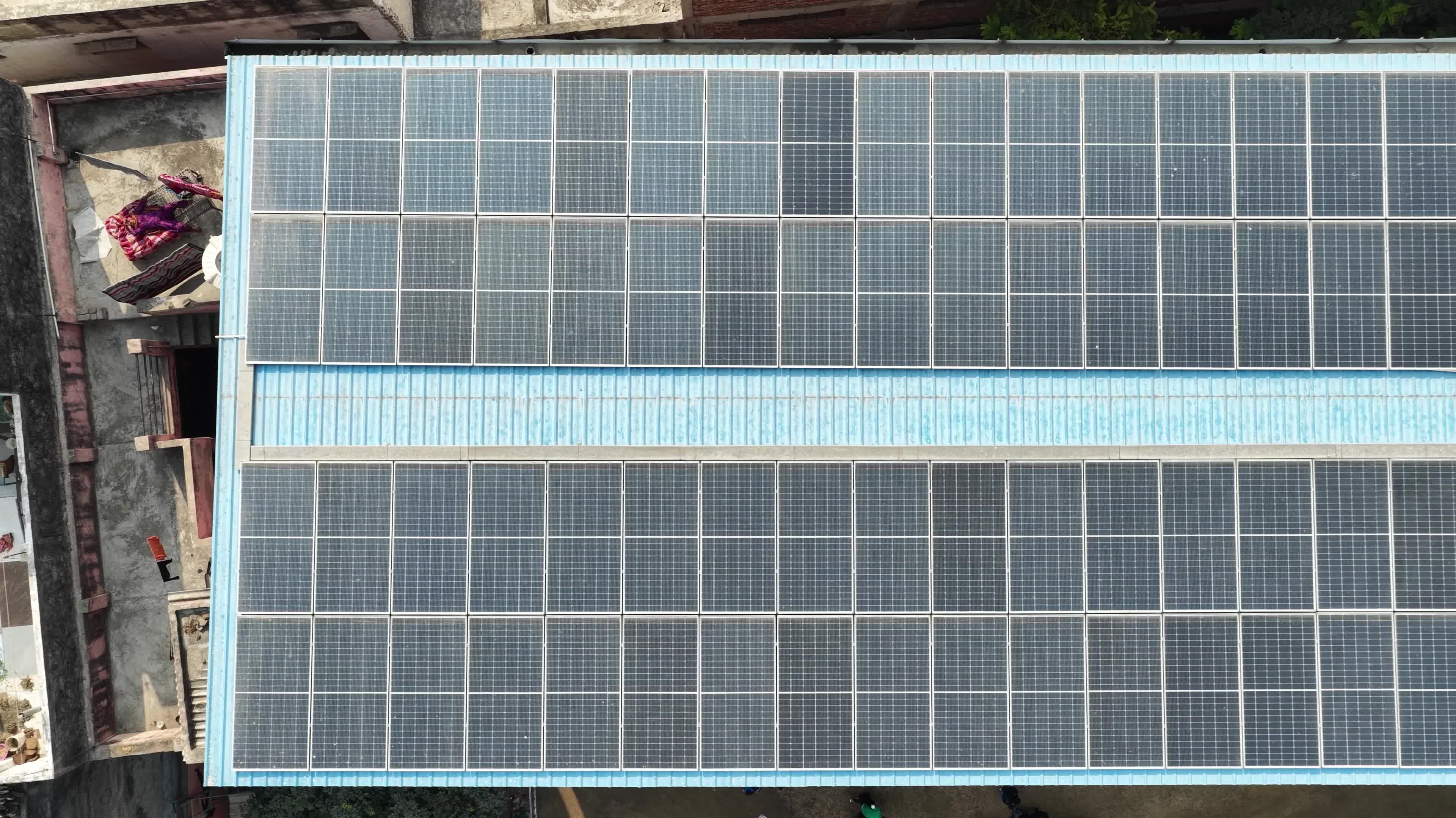 4K Aerial Drone View of Solar Panels Installed on Blue Tin Roof of Industrial Building in India