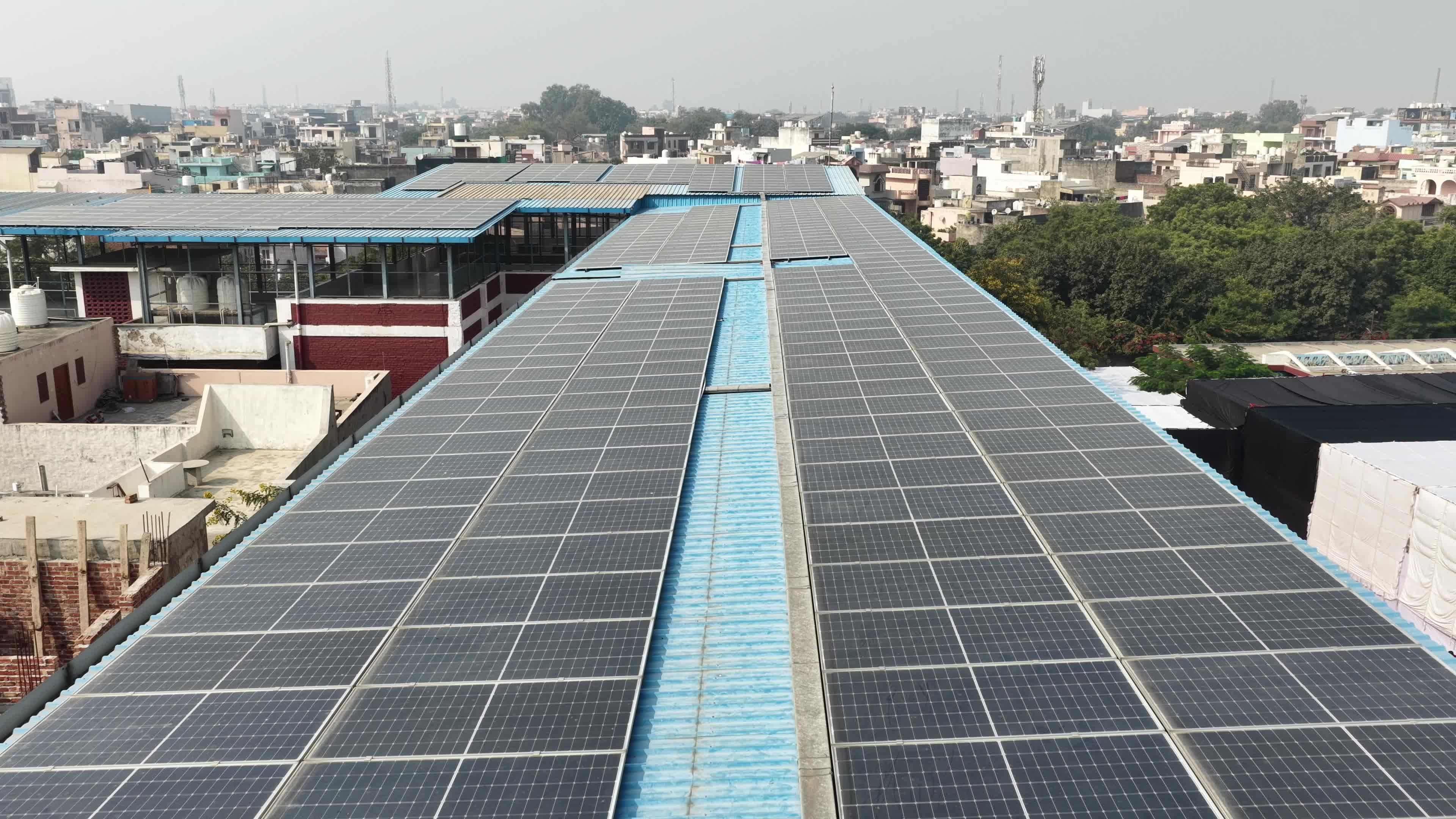 4K Aerial Drone View of Solar Panels Installed on Blue Tin Roof of Industrial Building in India