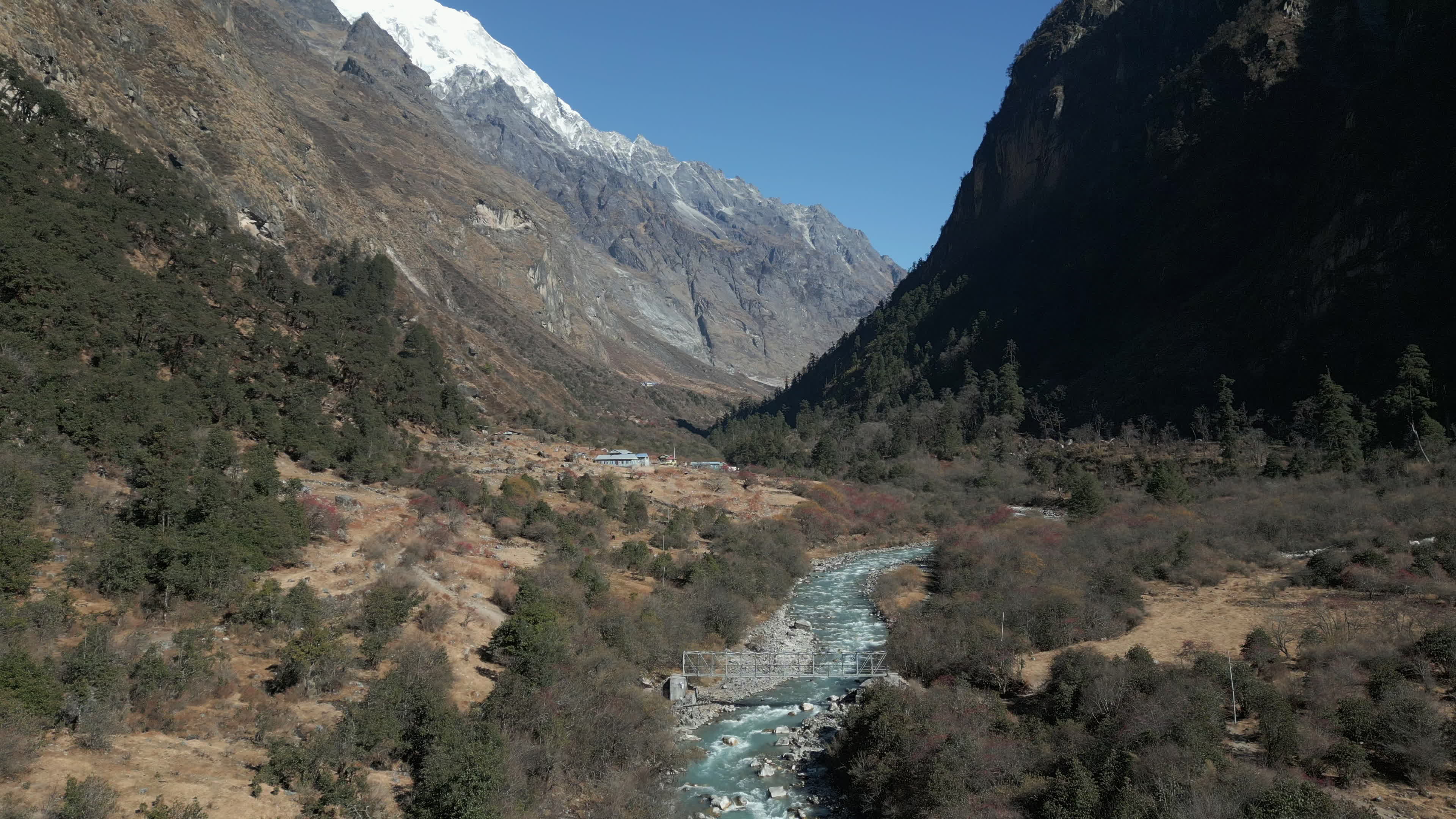 Himalayan Valley With Metal Bridge, Snow-Capped Peaks, and Mountain Settlements in Langtang