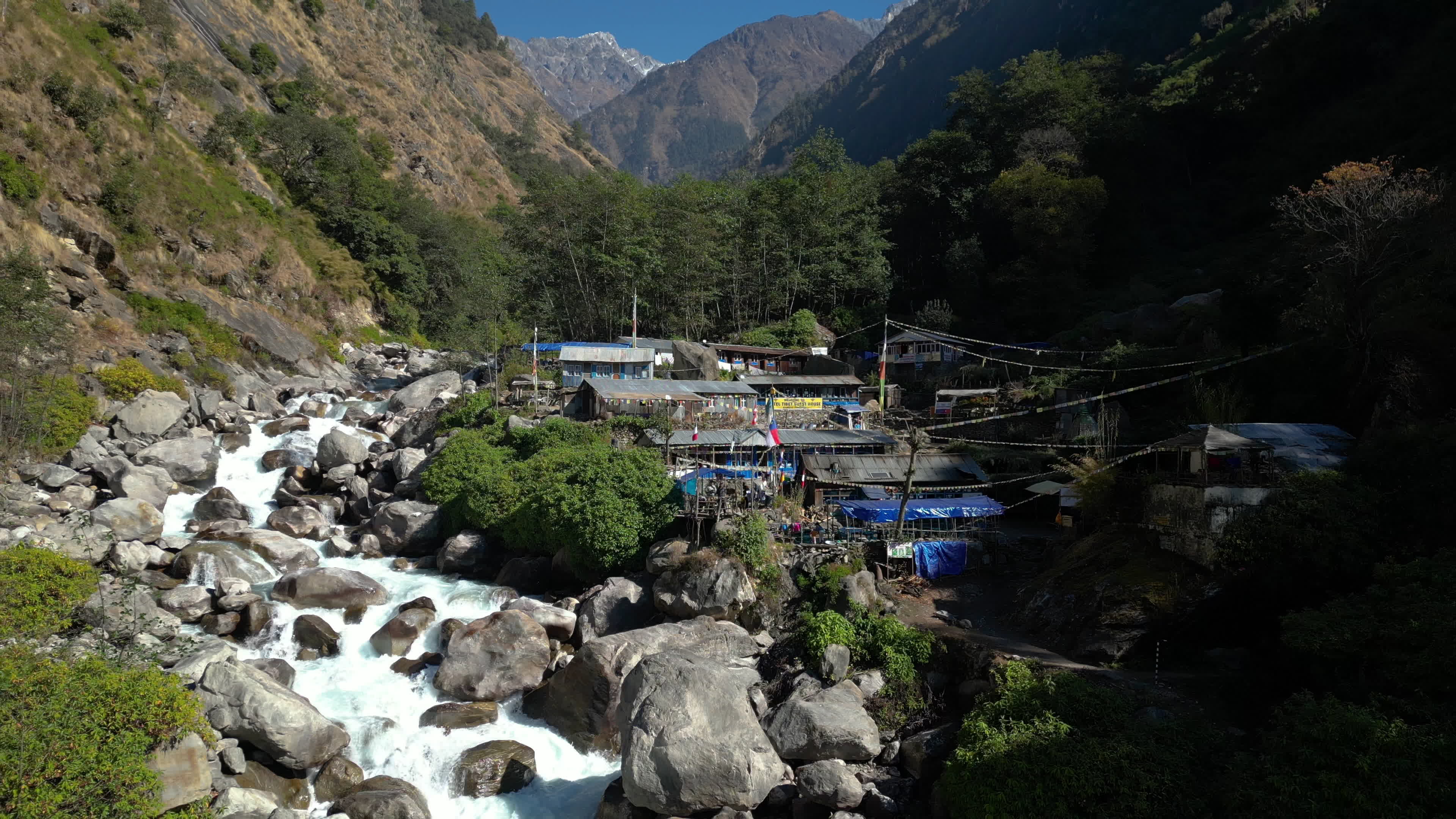 Langtang Trek River Valley With Teahouses and Distant Snow-Capped Mountains Aerial view