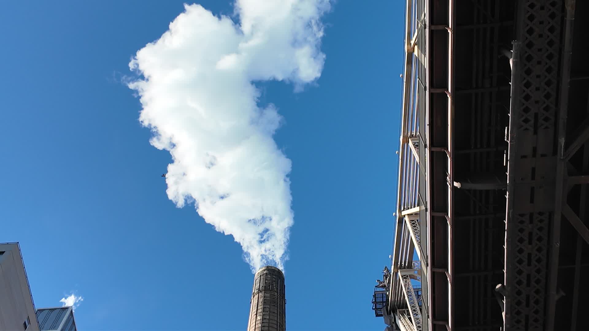A smoke stack extracts smoke next to the Queensboro Bridge