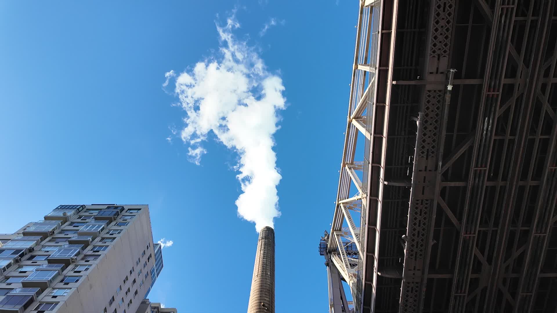 A smoke stack extracts smoke next to the Queensboro Bridge