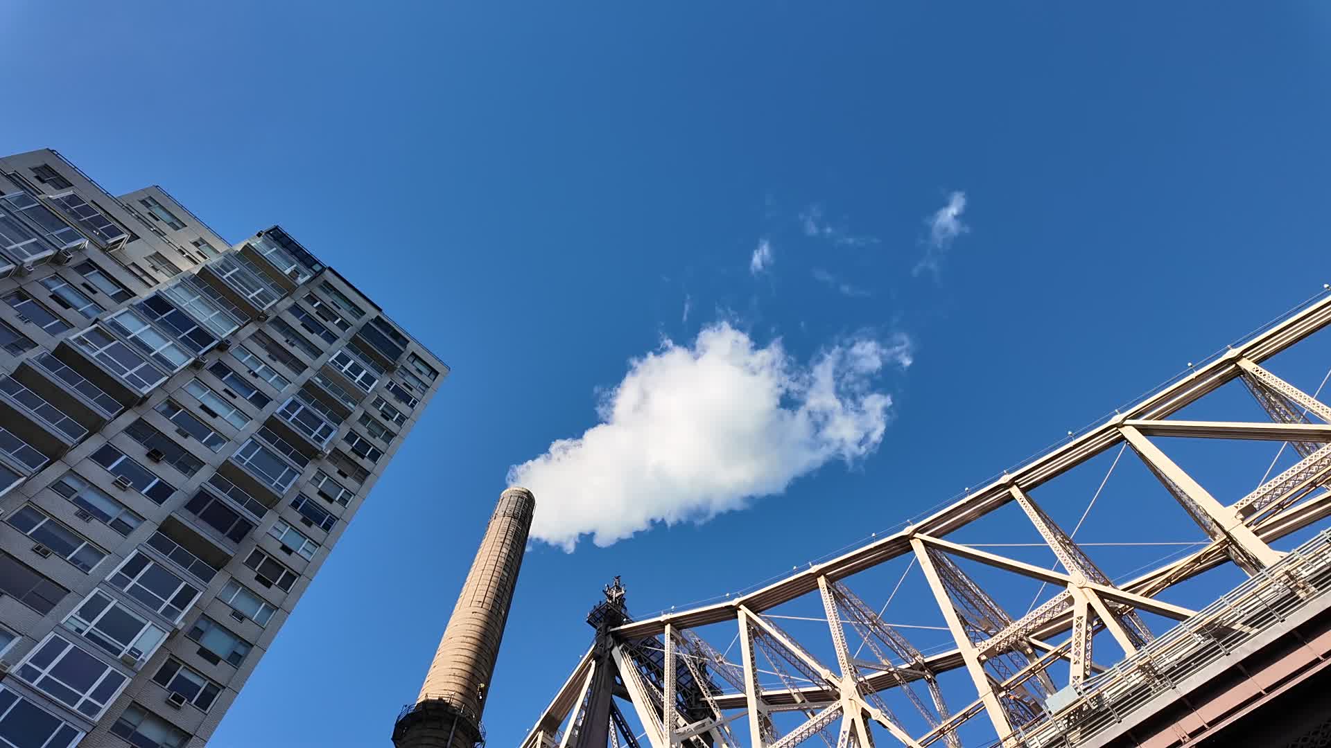 A smoke stack extracts smoke next to the Queensboro Bridge