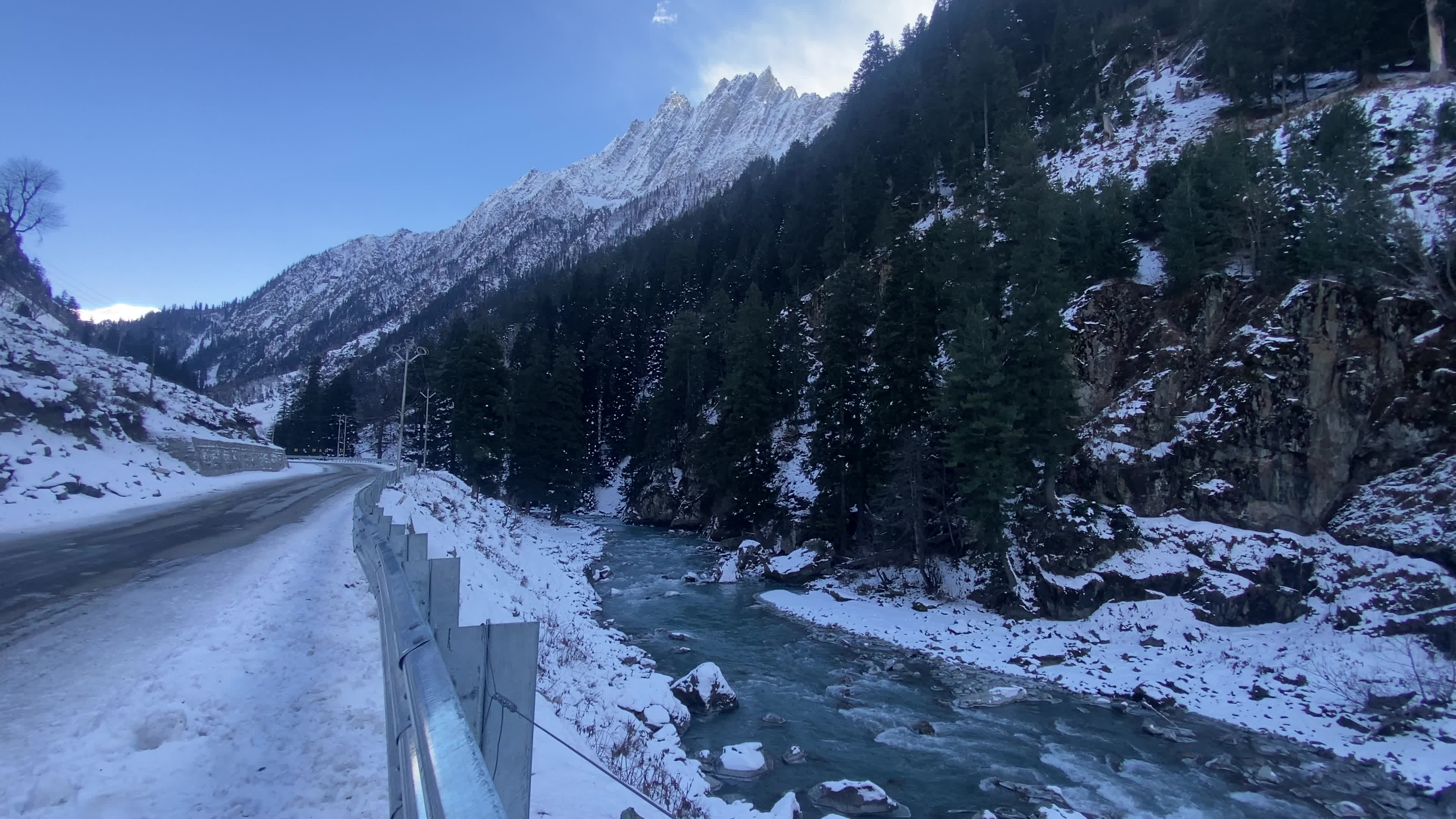 A view of a snow-covered road with snow-clad mountains in the background during winter