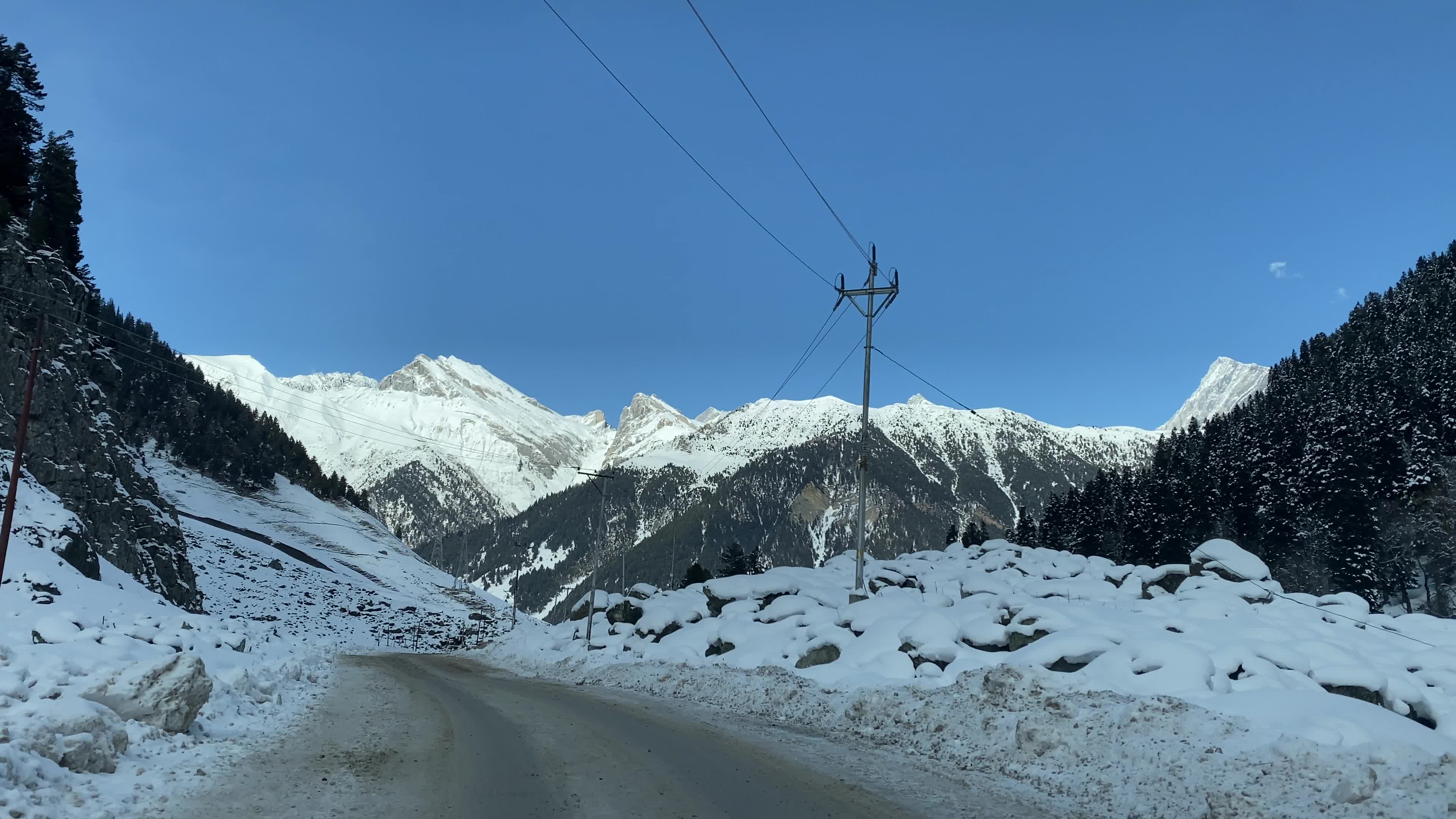 A view of a snow-covered road with snow-clad mountains in the background during winter.