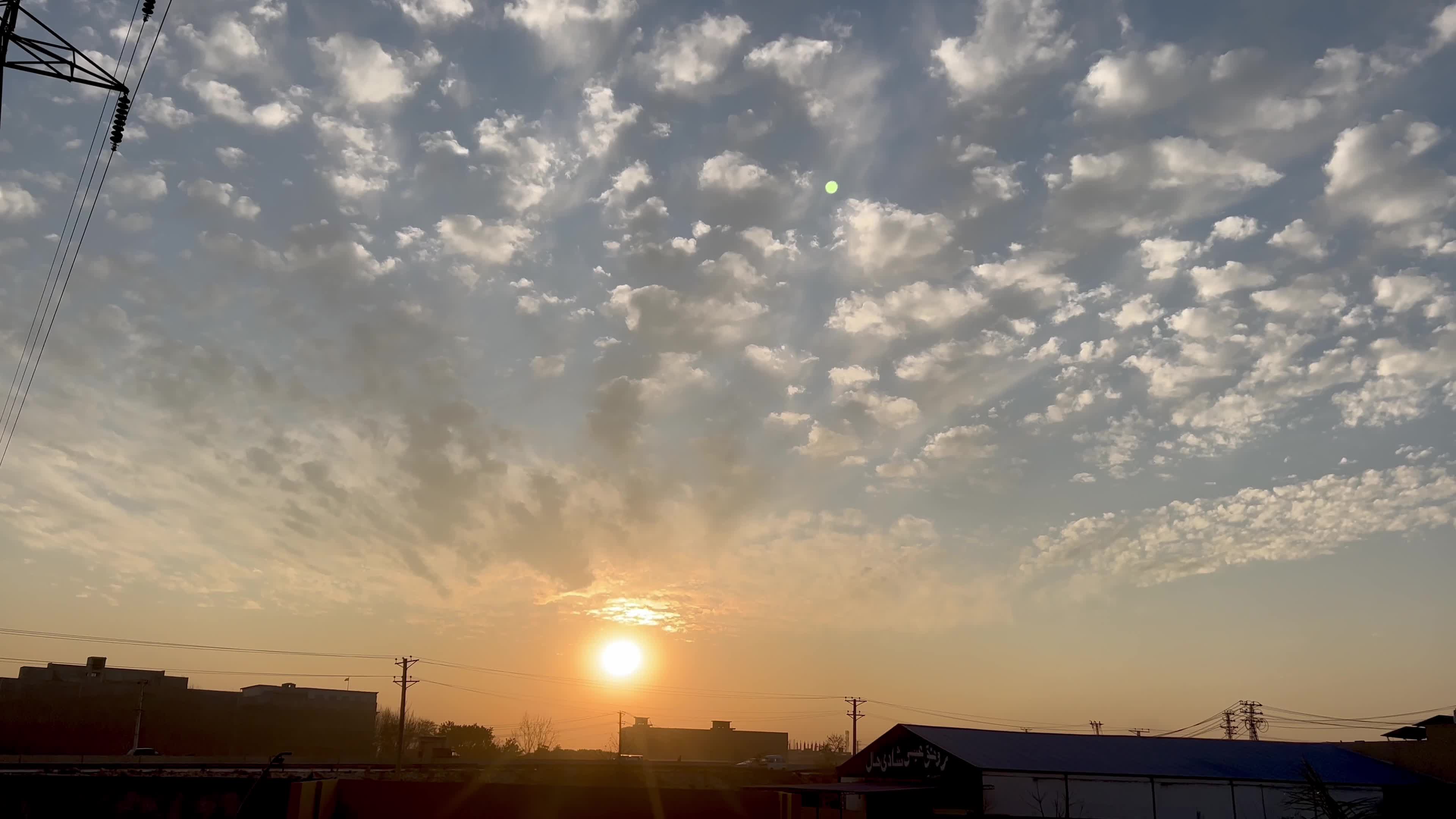 Sun sets beneath scattered clouds