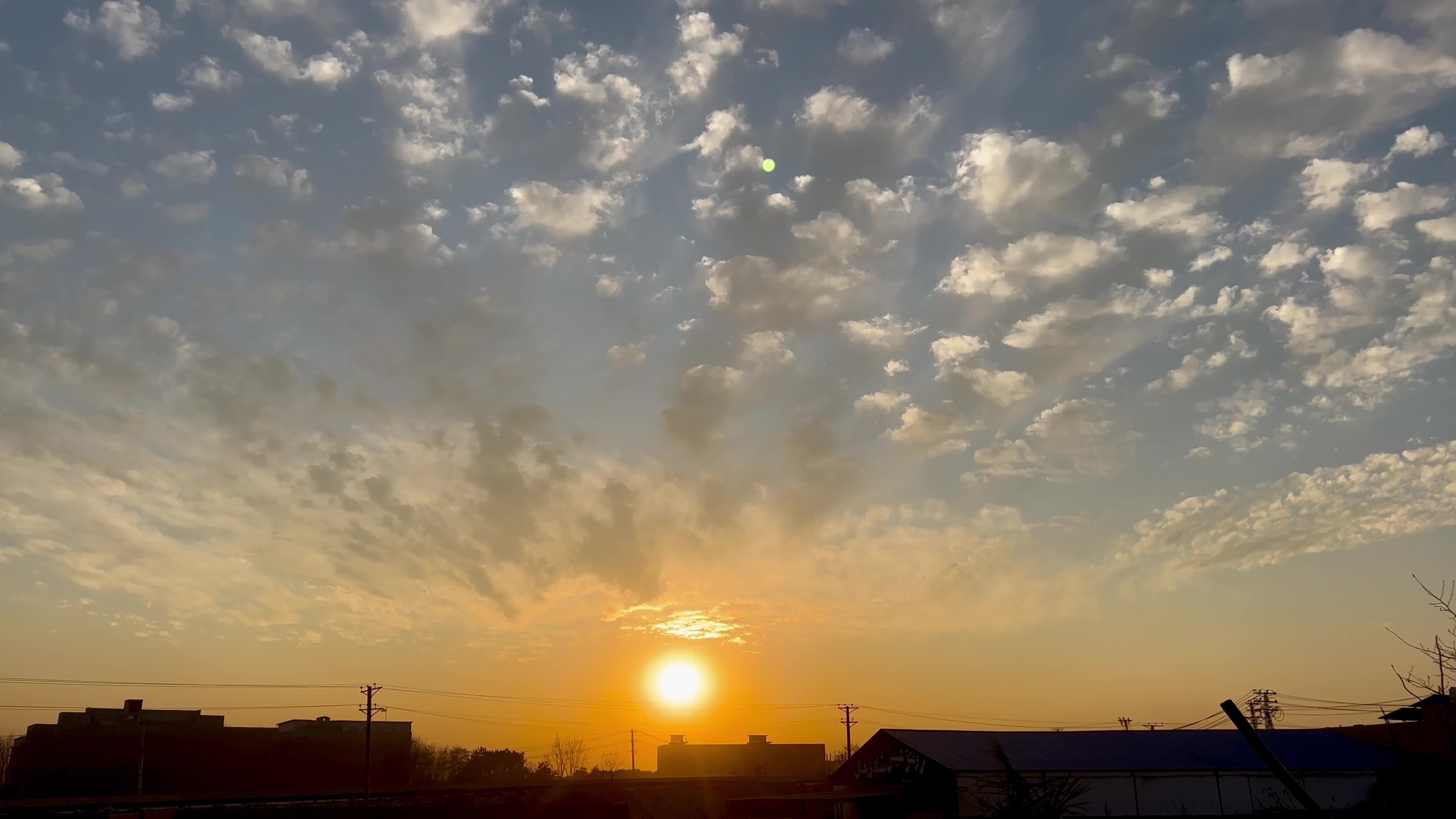 Sun sets beneath scattered clouds