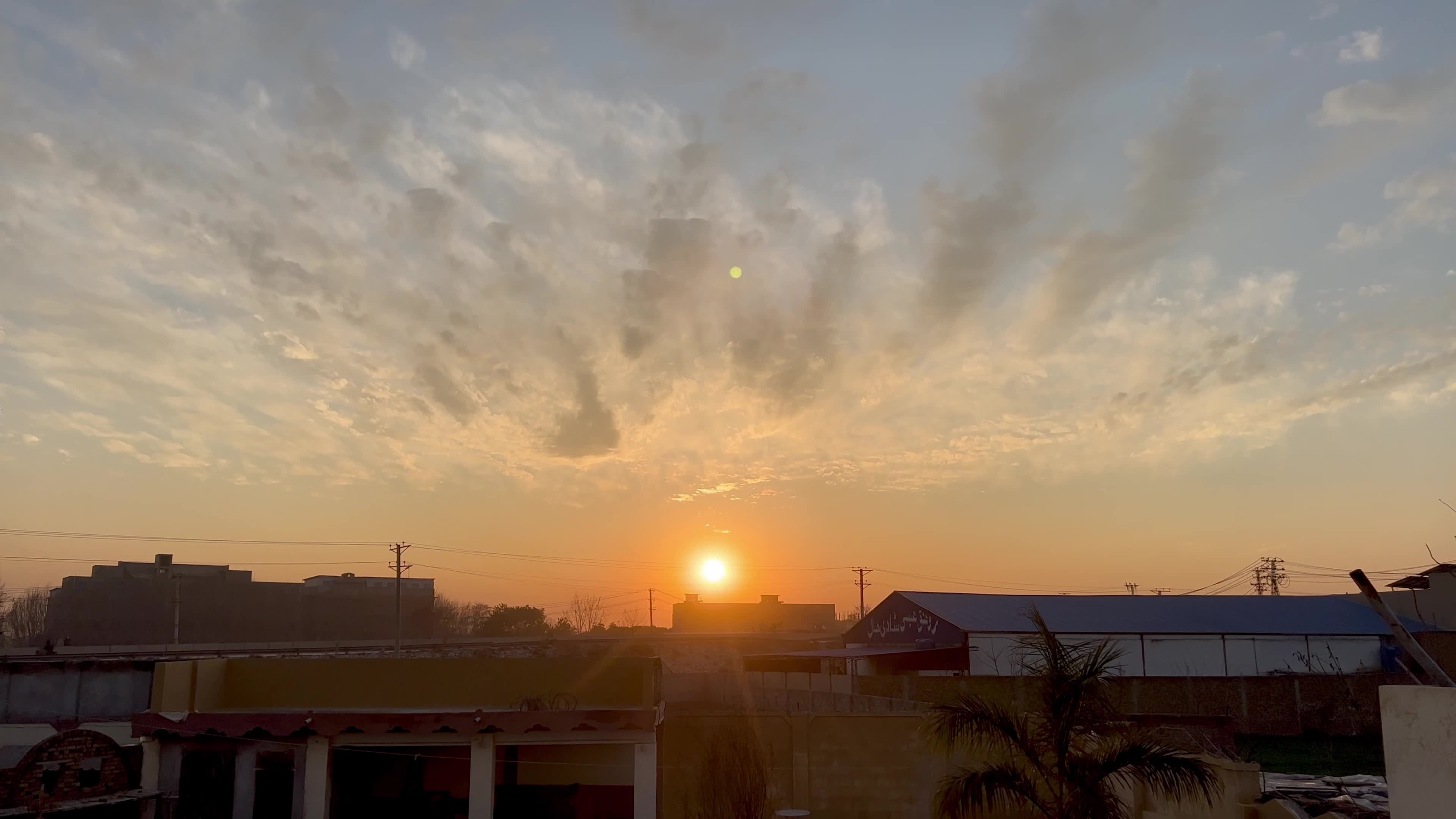 Sun sets beneath scattered clouds