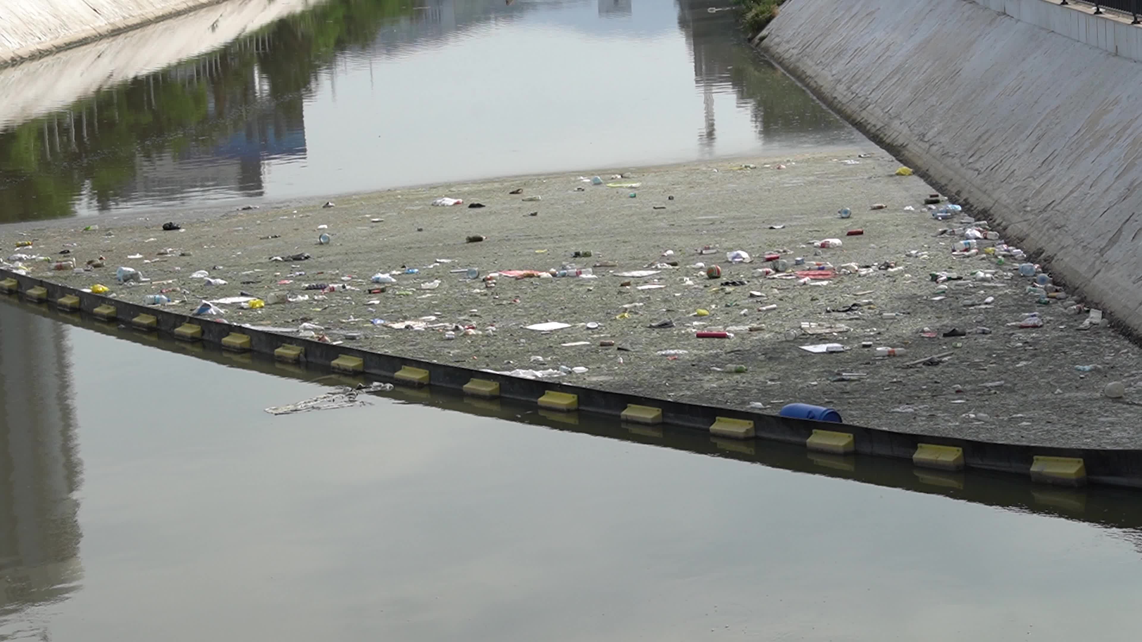 Trash and plastic bottles floating in a dirty city river