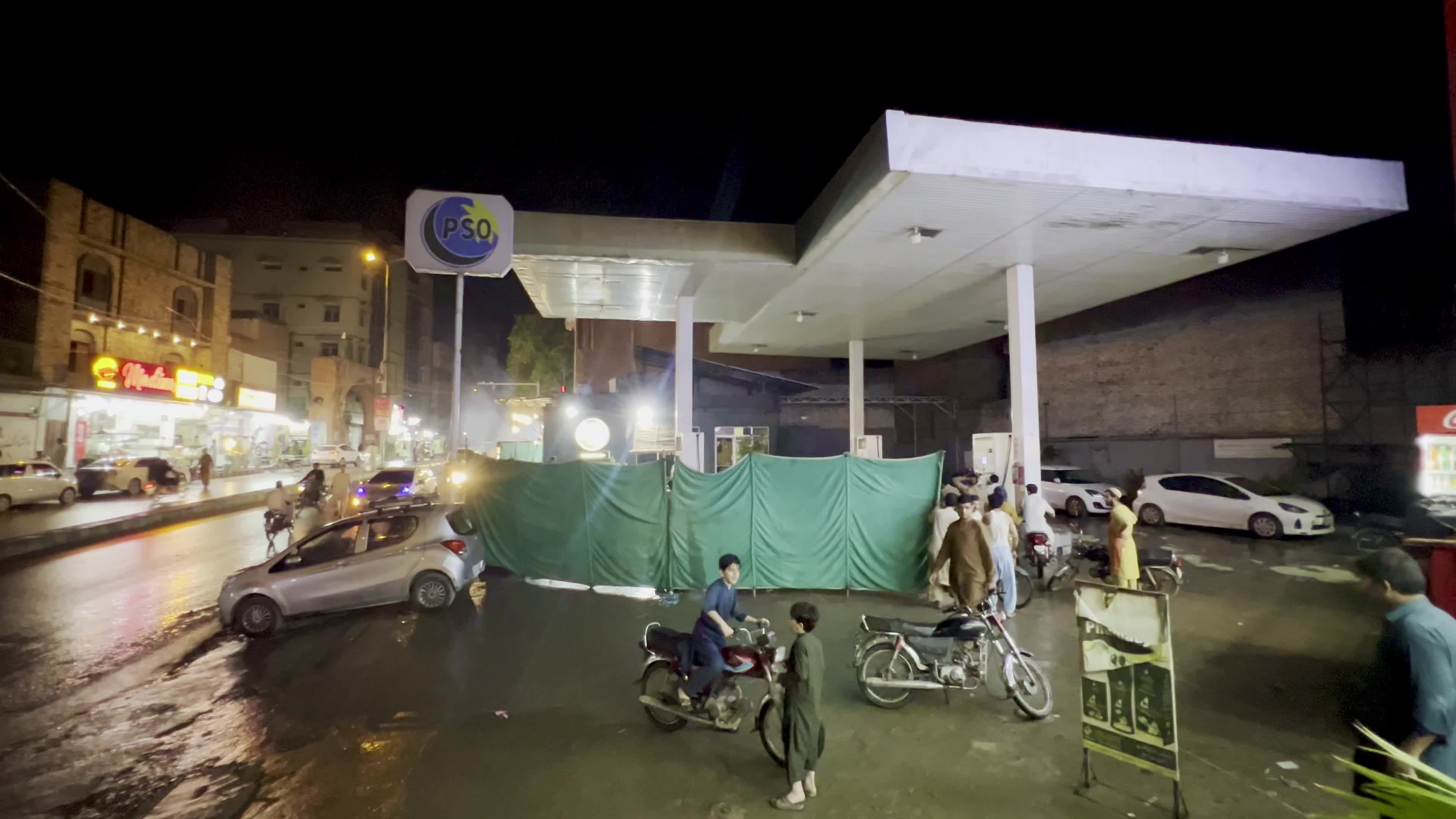 Petrol pump attendants stand beside covered fuel dispensers after fuel price hike in Peshawar
