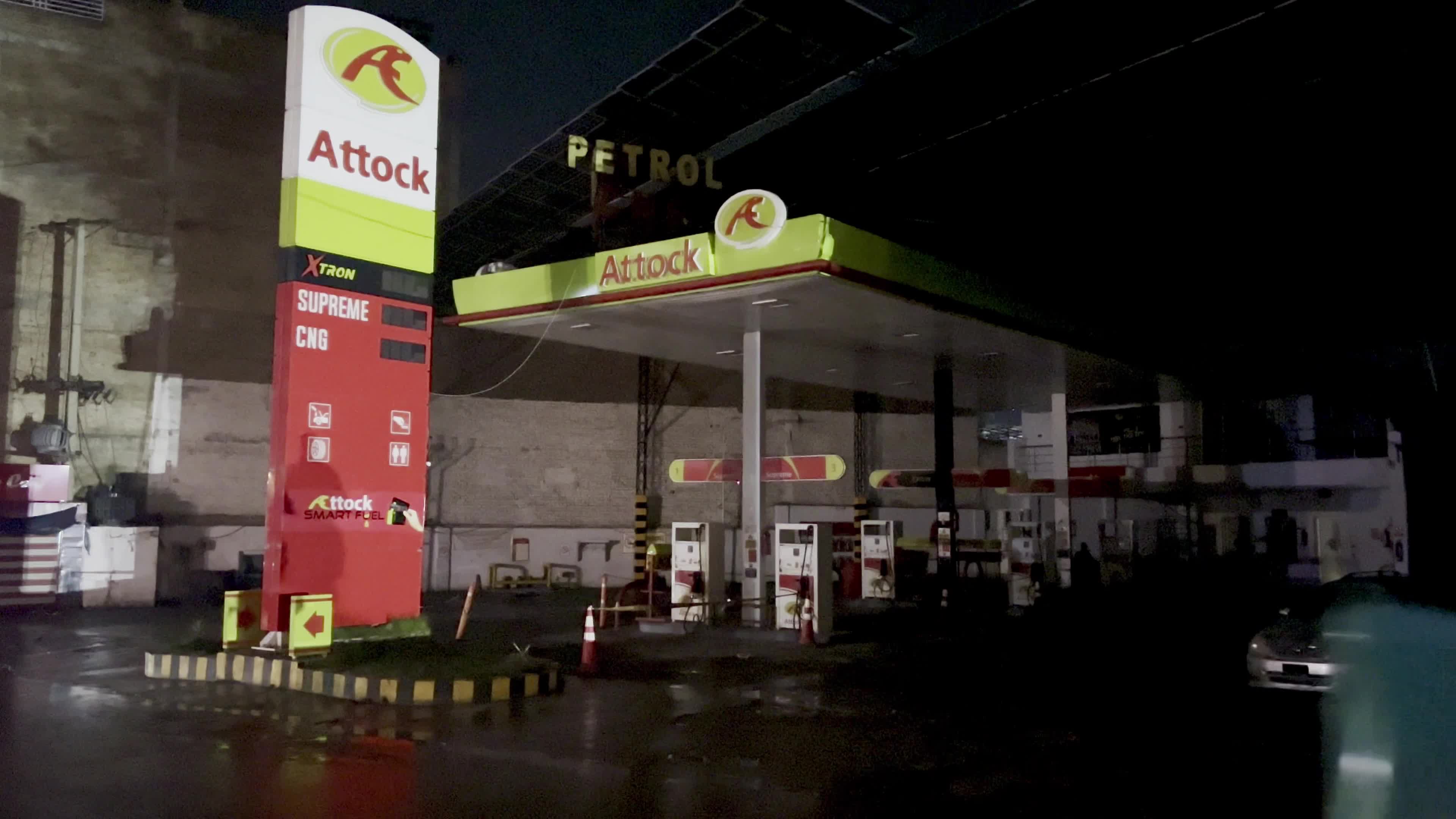 Petrol pump attendants stand beside covered fuel dispensers after fuel price hike in Peshawar