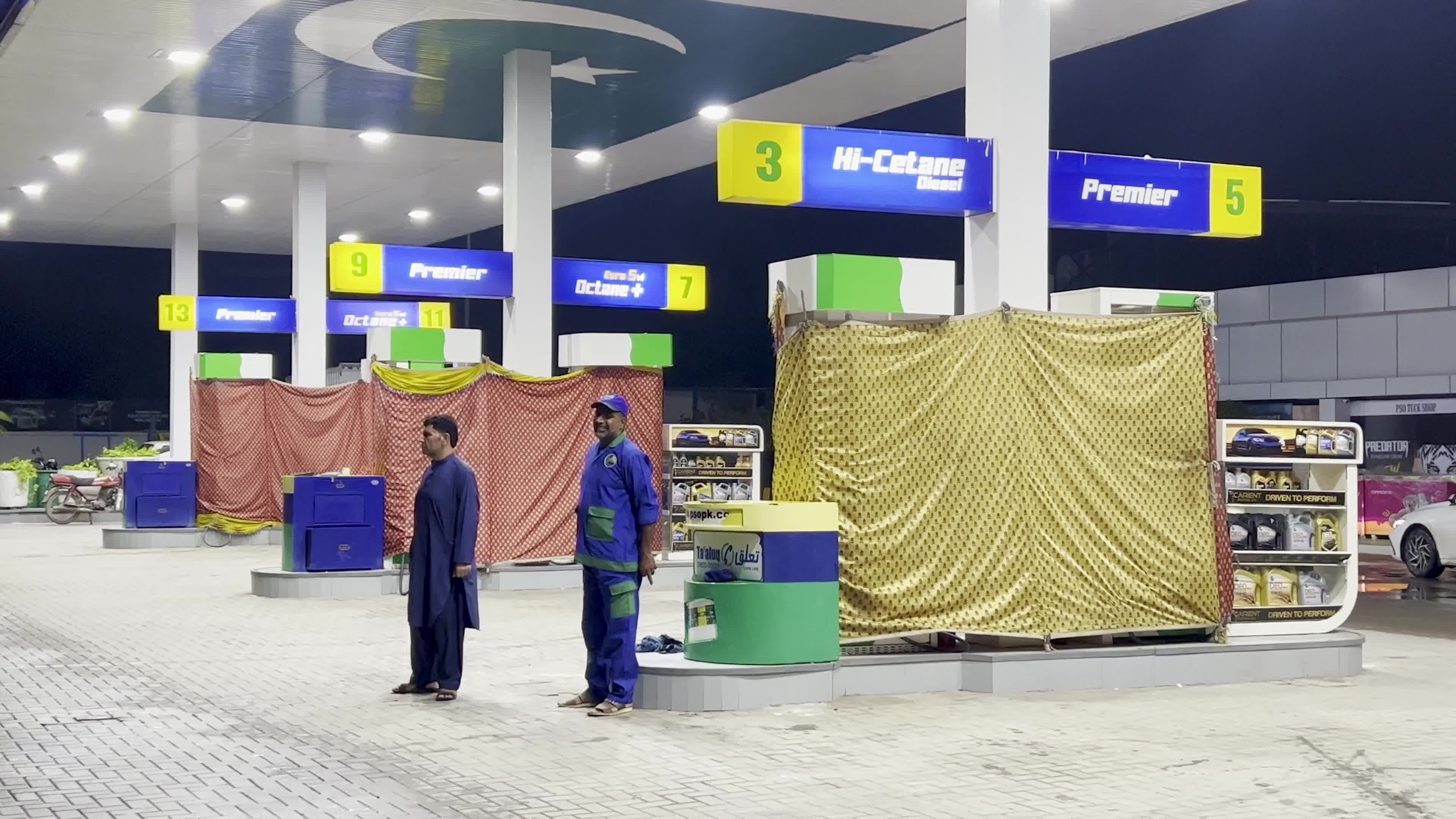 Petrol pump attendants stand beside covered fuel dispensers after fuel price hike in Peshawar